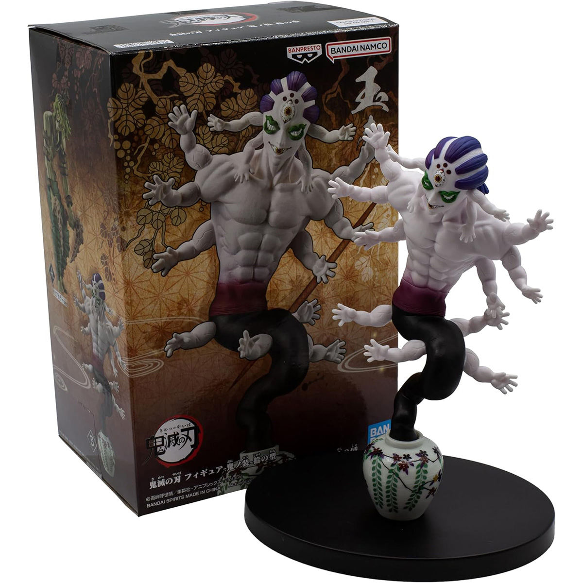 Figura de anime con muchos brazos, una caja negra y un jarrón. La figura es gris con cabello morado.