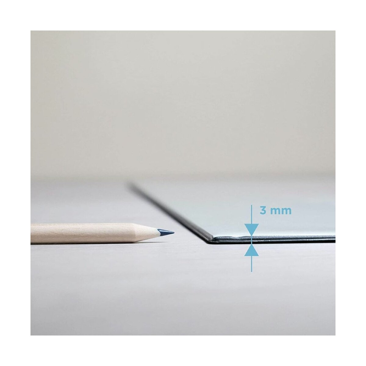 Ein Bleistift neben einer dünnen, grauen Metallplatte. Die Platte ist 3 mm dick. Weißer Hintergrund.