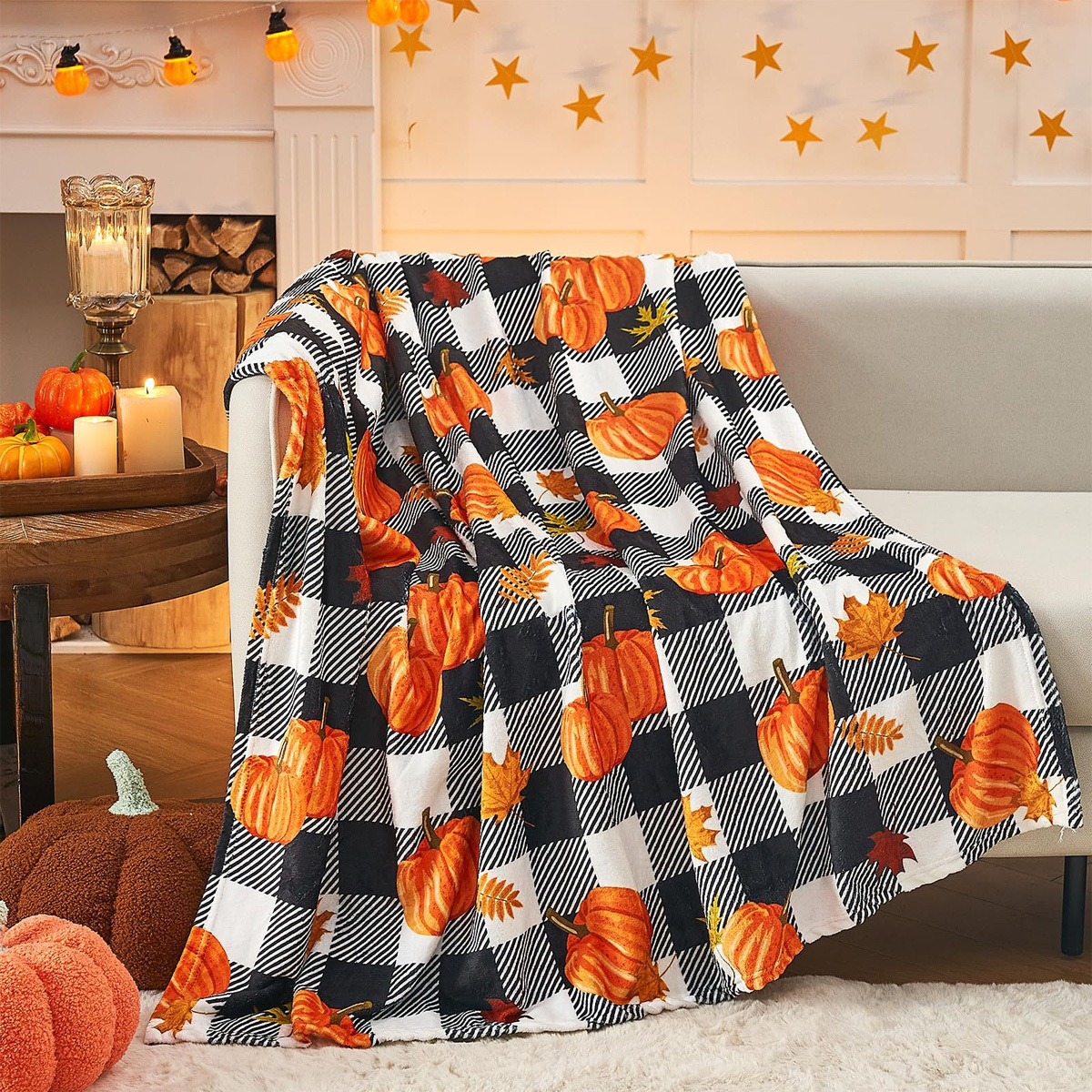 Eine herbstliche karierte Decke mit Kürbissen und Herbstblättern auf einer weißen Couch.