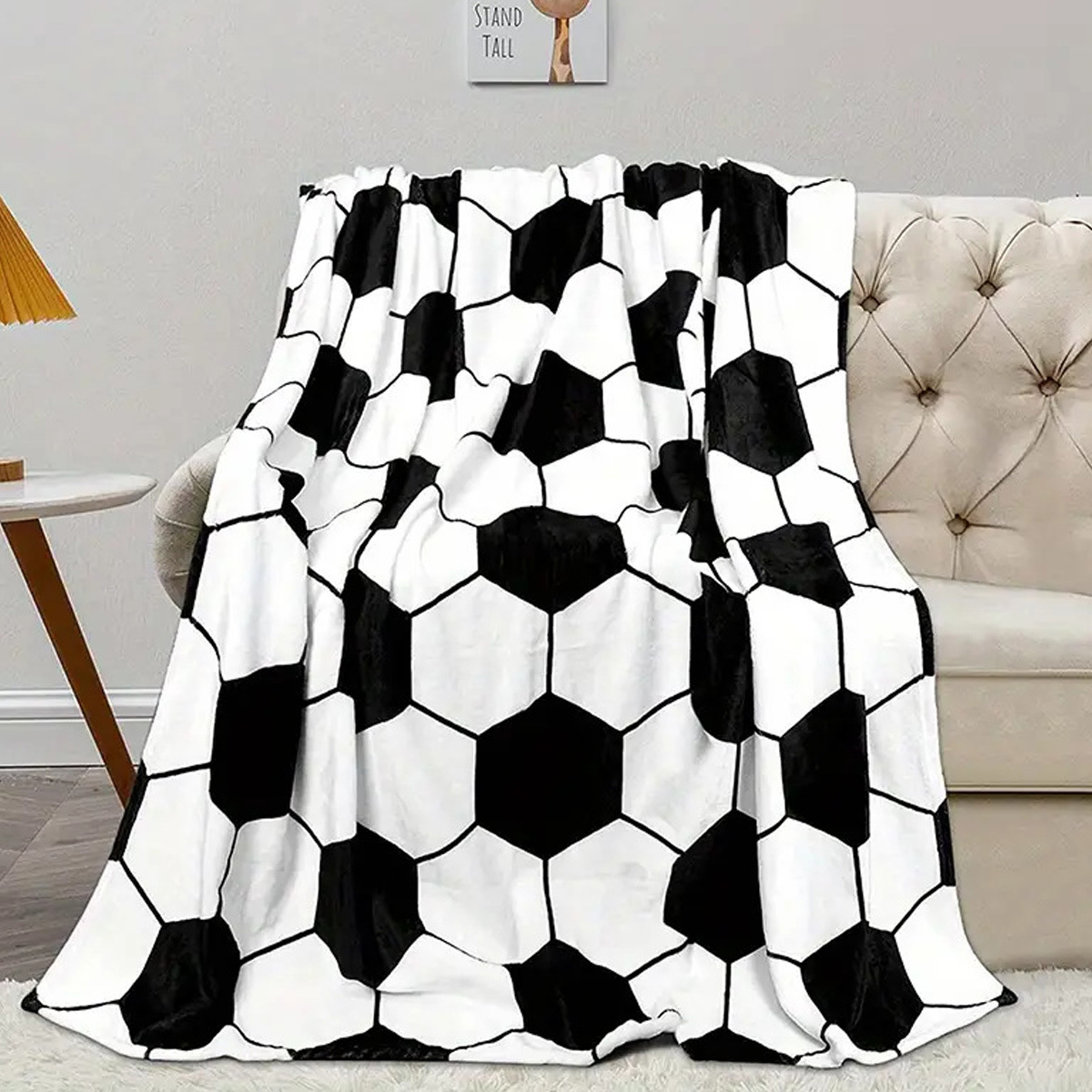 Eine Fußball-Musterdecke über einem weißen Sofa, mit neutralem Hintergrund.