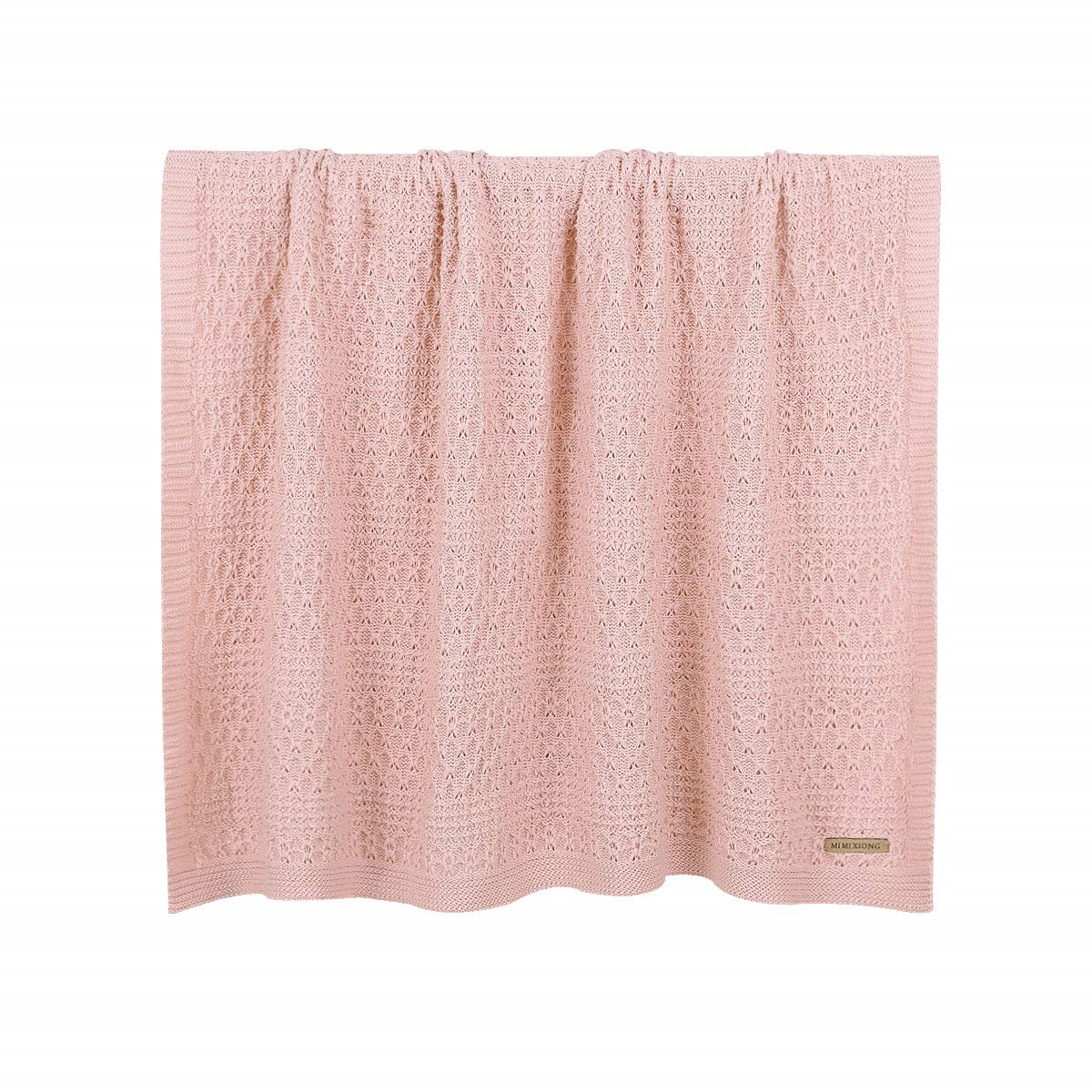 Rosa gestrickte Babydecke mit Etikett unten, auf weißem Hintergrund.
