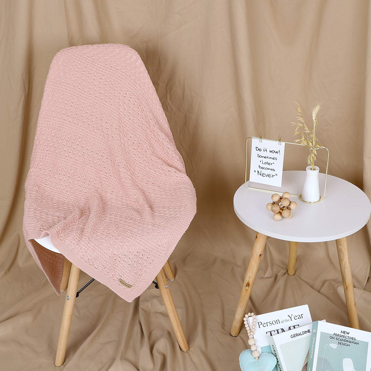 Rosa Decke über einem weißen Stuhl. Kleiner Tisch mit Deko. Tan-farbener Hintergrund.