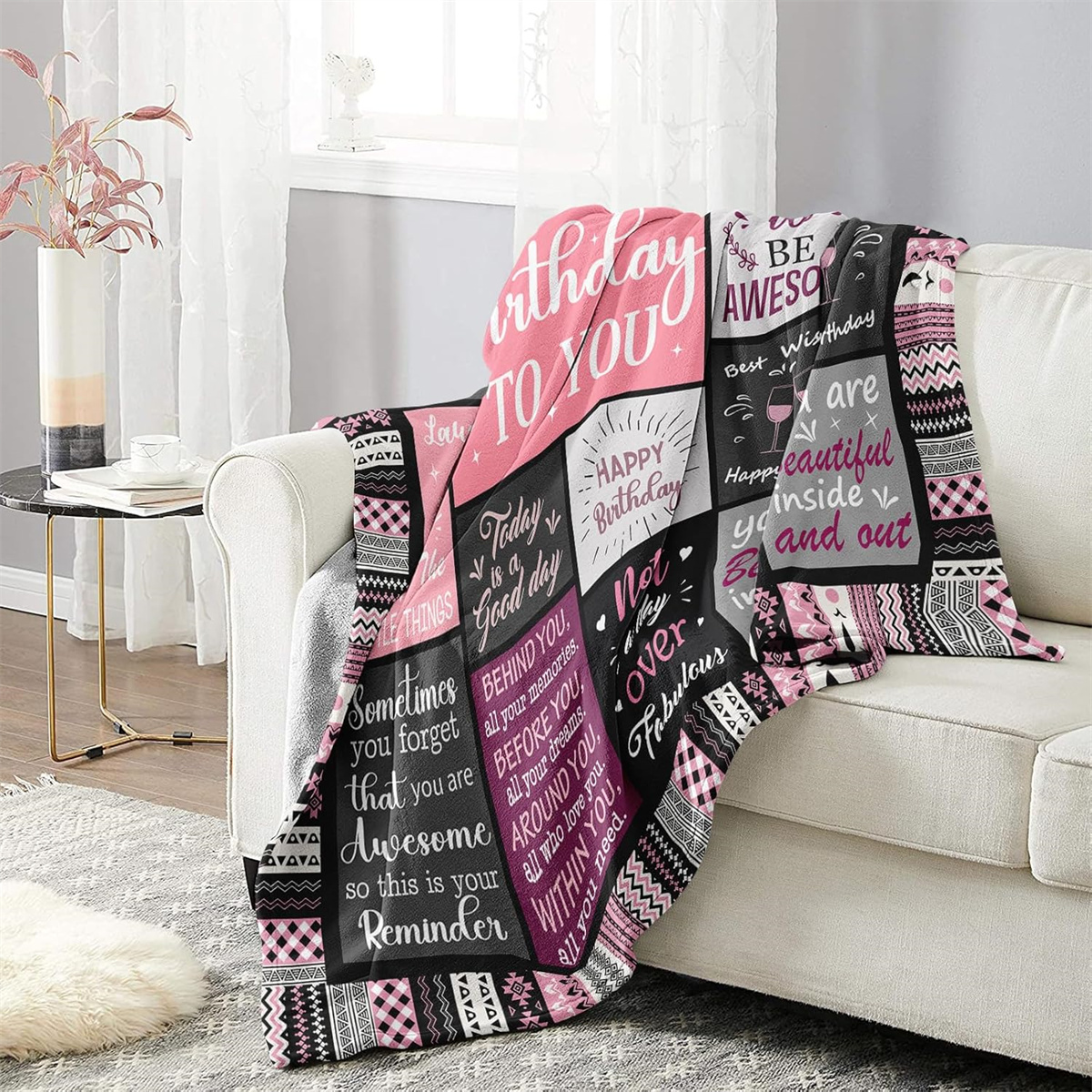 Sofa mit Decke mit Geburtstagswünschen und rosa Akzenten. Die Decke ist gefaltet.