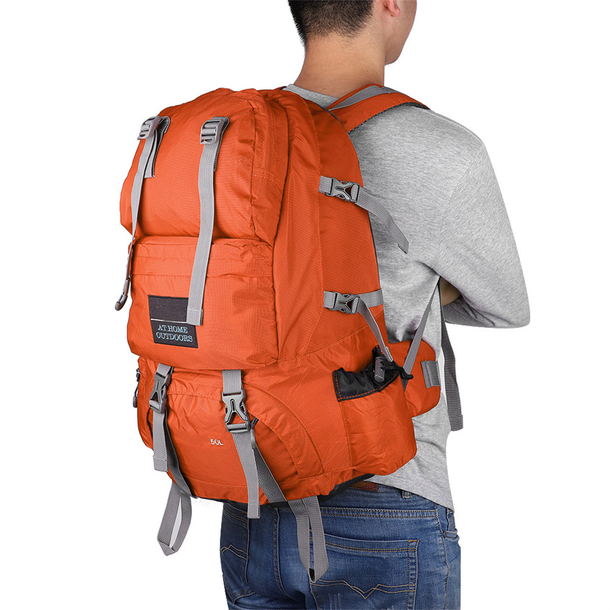 Ein Mann mit einem orangefarbenen Rucksack steht mit dem Rücken zur Kamera.
