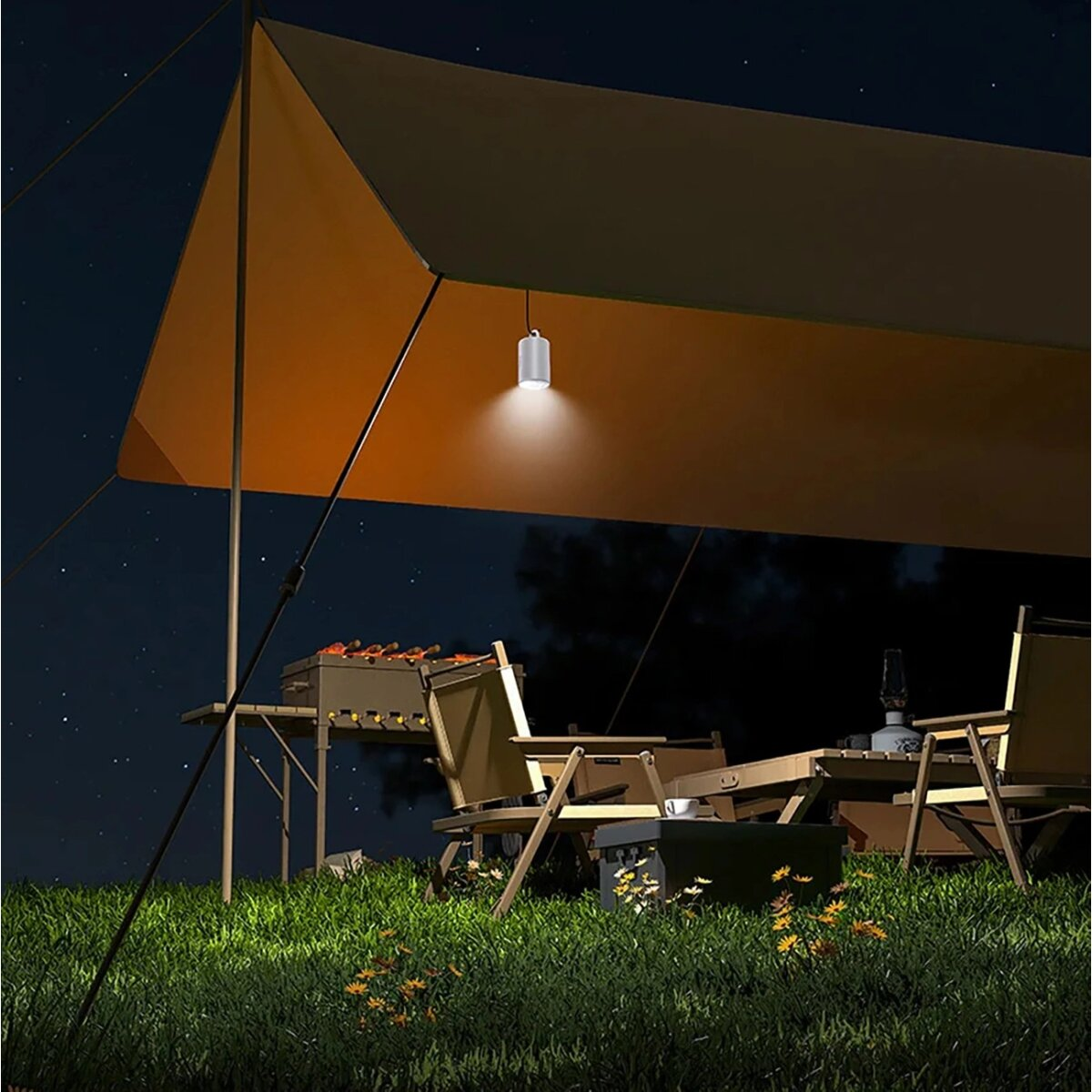 Camping-Szene bei Nacht mit beleuchtetem Zelt, Tisch, Stühlen und Lagerfeuer.