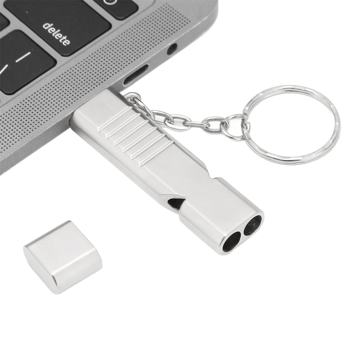 Silberne Pfeife USB-Stick mit Schlüsselanhänger, eine silberne Kappe zur Seite und ein Laptop im Hintergrund.
