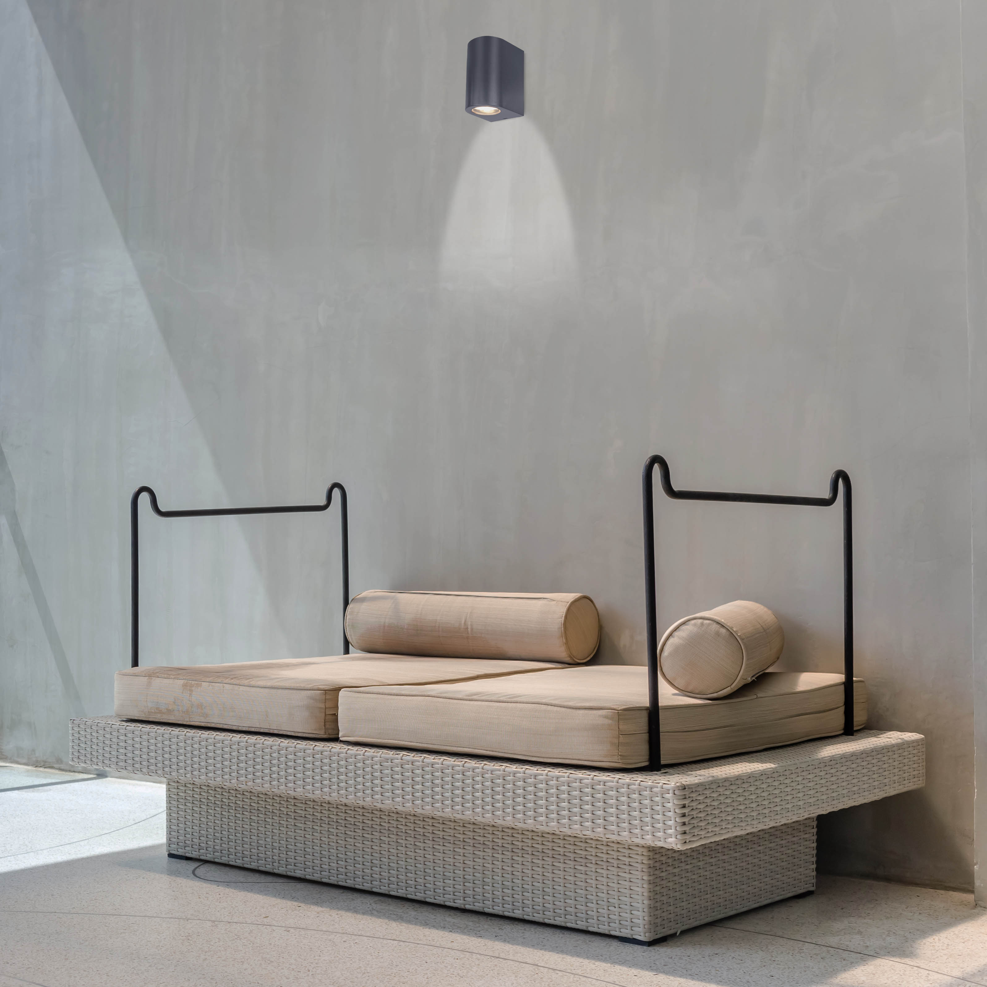 Außenbereich mit hellgrauer Wand, modernem Sofa und Deckenleuchte.