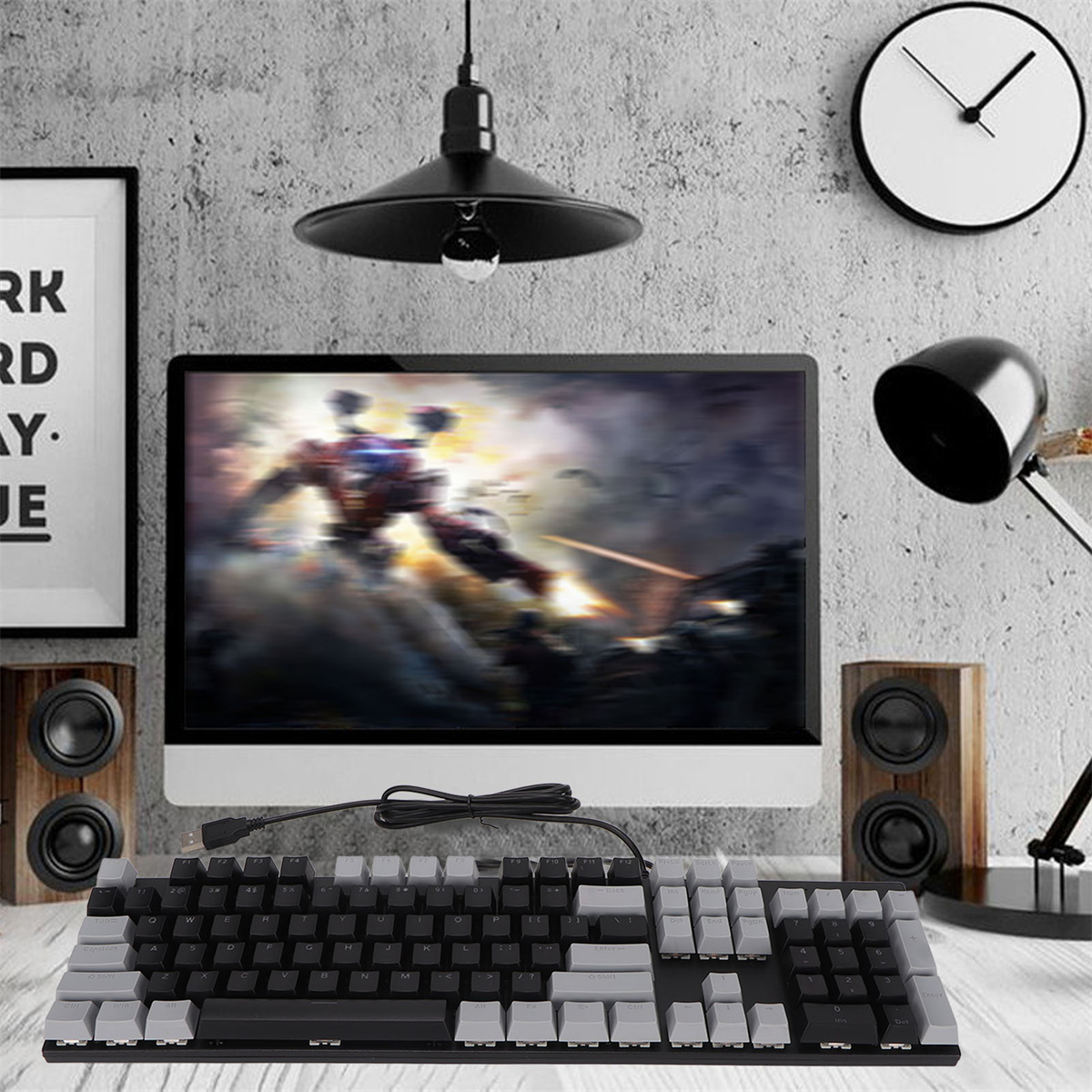 Computer-Setup mit Tastatur, Lautsprechern, Monitor und Lampe. Der Hintergrund umfasst eine Wand mit gerahmter Kunst und einer Uhr.