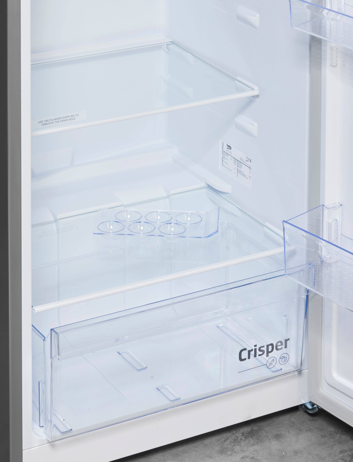 Interno di un frigorifero bianco aperto con ripiani, cassetto per verdura e scomparti trasparenti.
