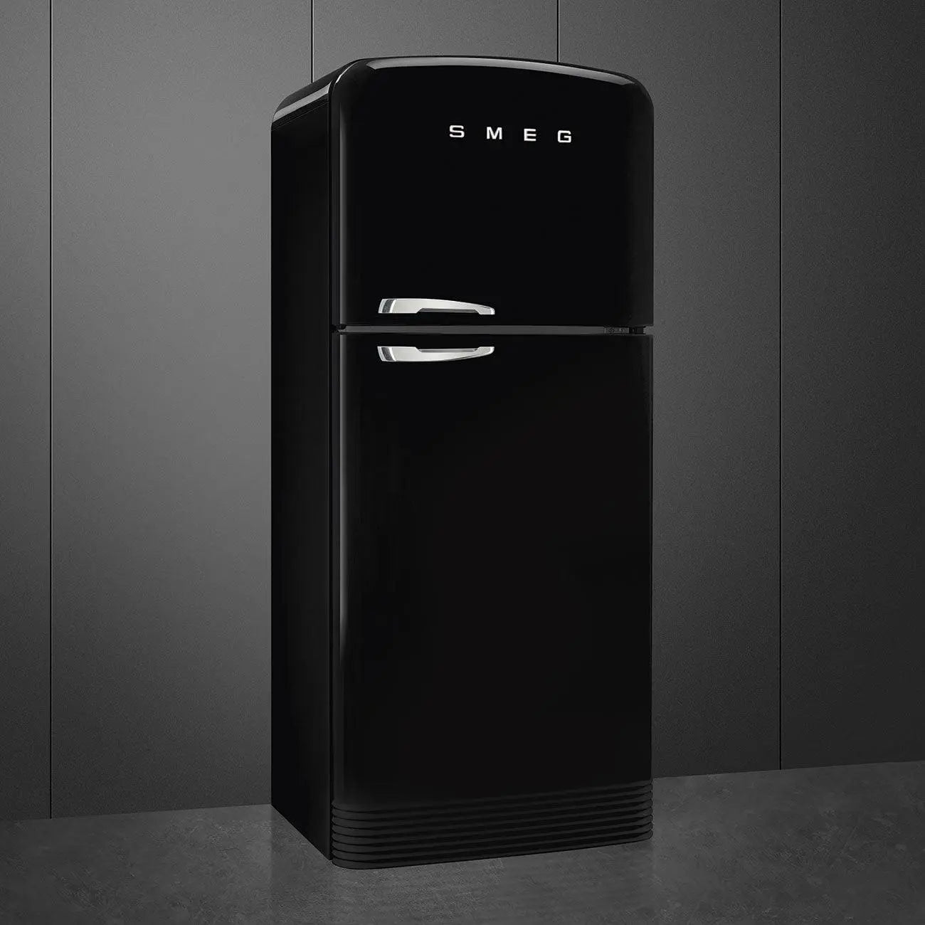 Refrigerador SMEG negro de estilo retro con dos puertas, asas plateadas, contra pared gris oscuro.