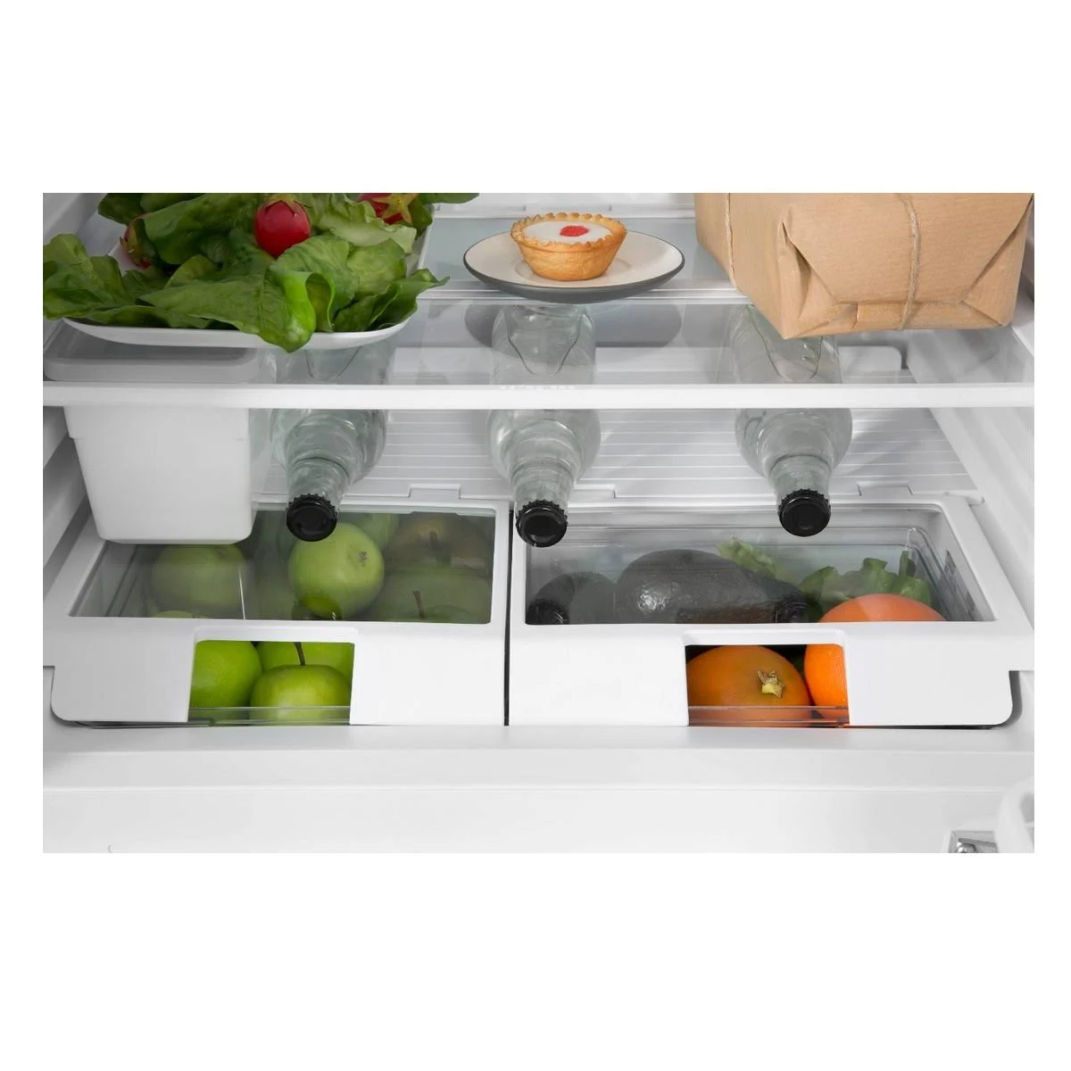 All'interno di un frigorifero pieno di cibo. Include frutta, verdura, bottiglie e un piccolo pasticcino.