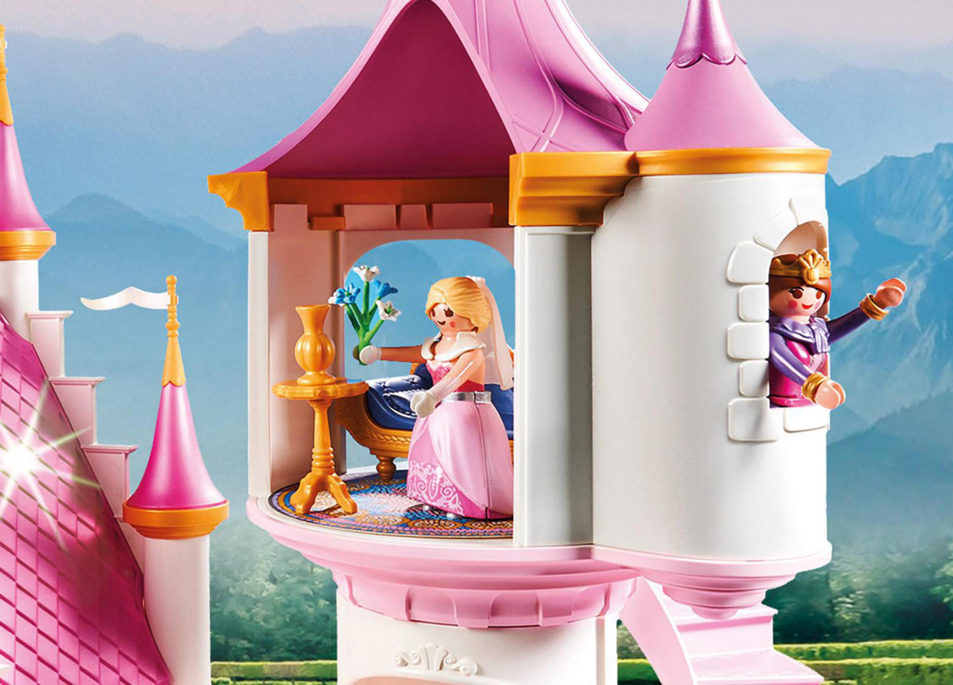 Spielzeugschloss mit zwei Figuren. Eine am Tisch mit Blumen, die andere im Turm.