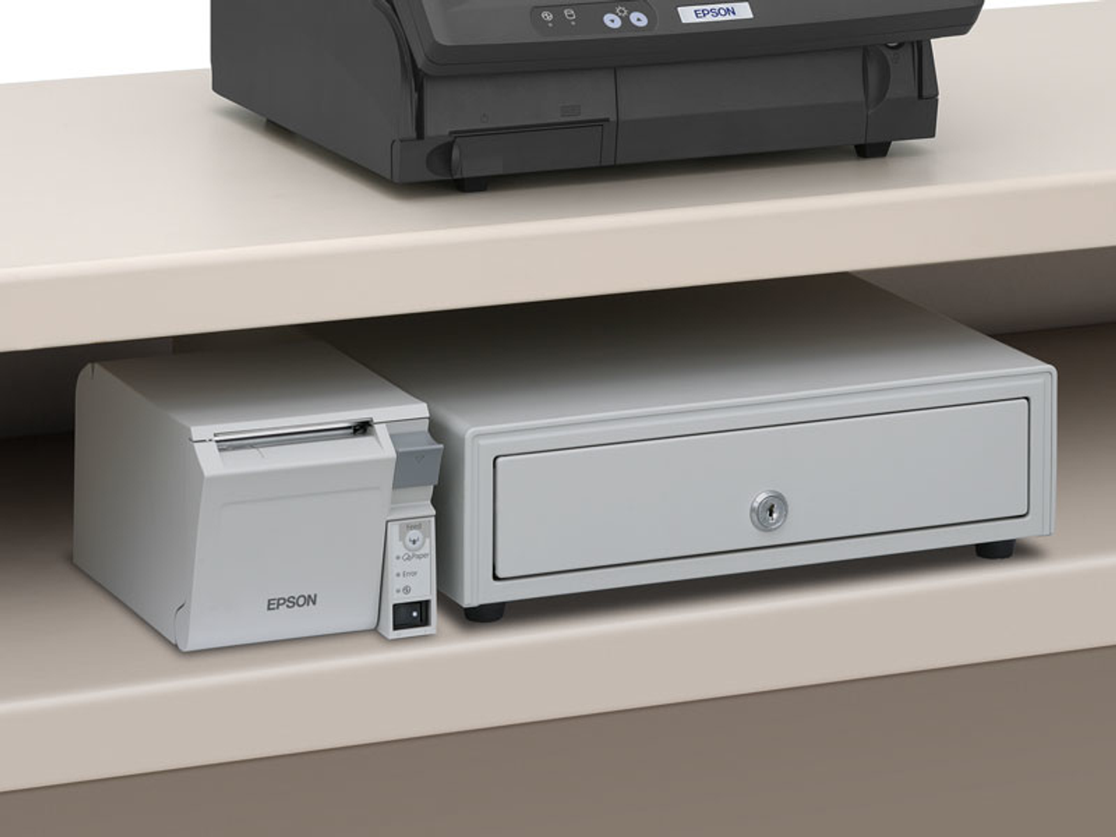 Imprimante et caisse enregistreuse dans un tiroir. L'imprimante Epson est à gauche.