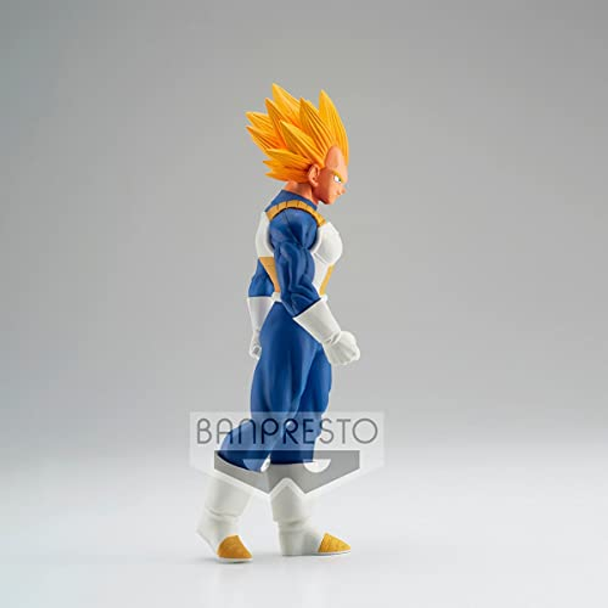 Vegeta-Figur in blau-weißem Outfit mit gelben Haaren, steht auf einer weißen Oberfläche.