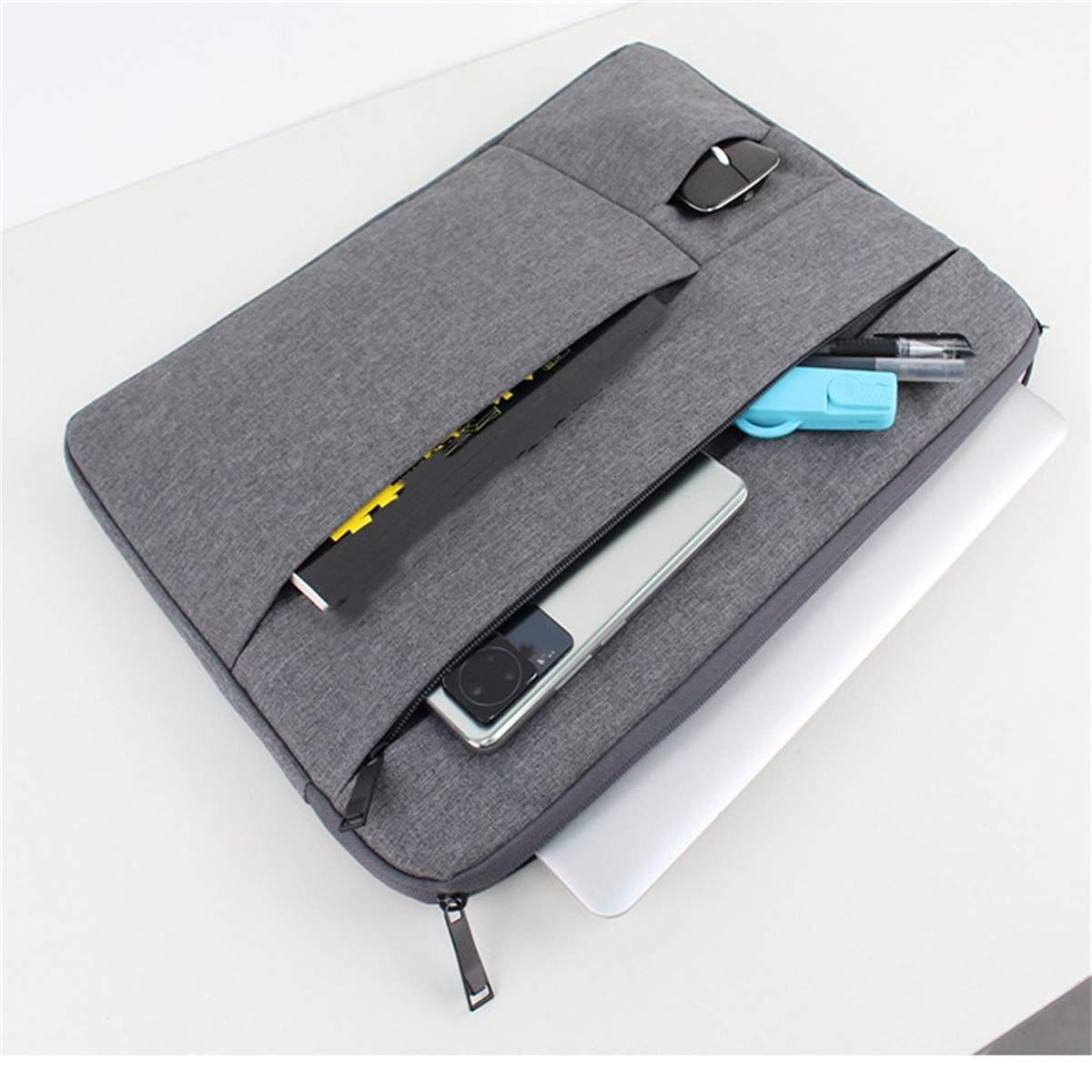 Eine graue Laptoptasche, geöffnet, mit einem Laptop, Telefon und anderem Zubehör darin.