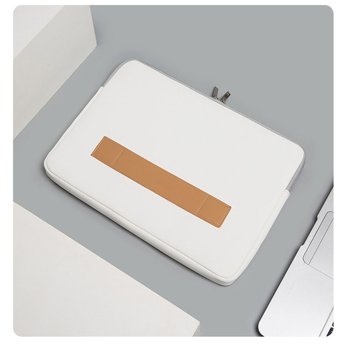 Eine weiße Laptop-Hülle mit braunen Lederakzenten. Die Hülle liegt auf einer grauen Oberfläche.