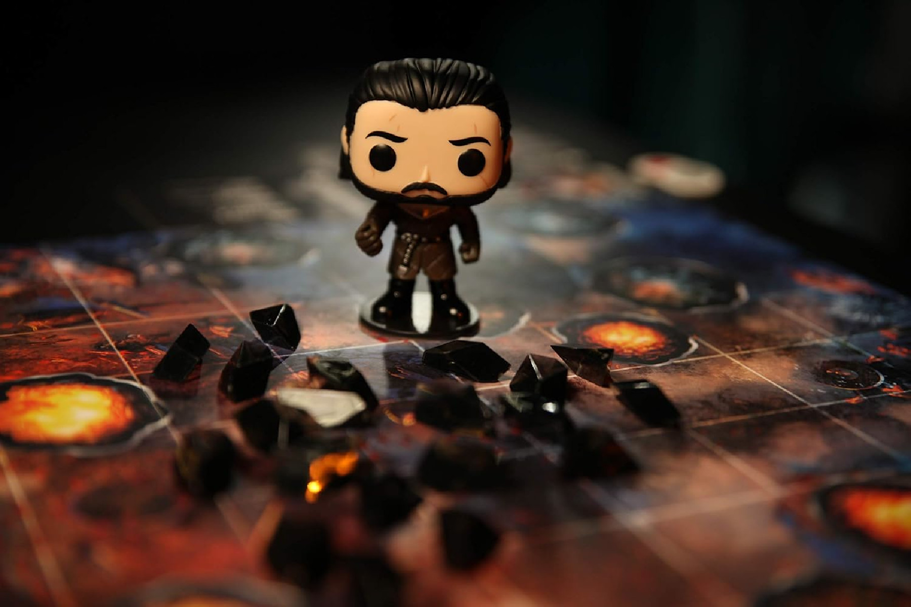 Eine Funko Pop Figur eines Mannes mit Bart auf einem Spielbrett mit verstreuten schwarzen Steinen.