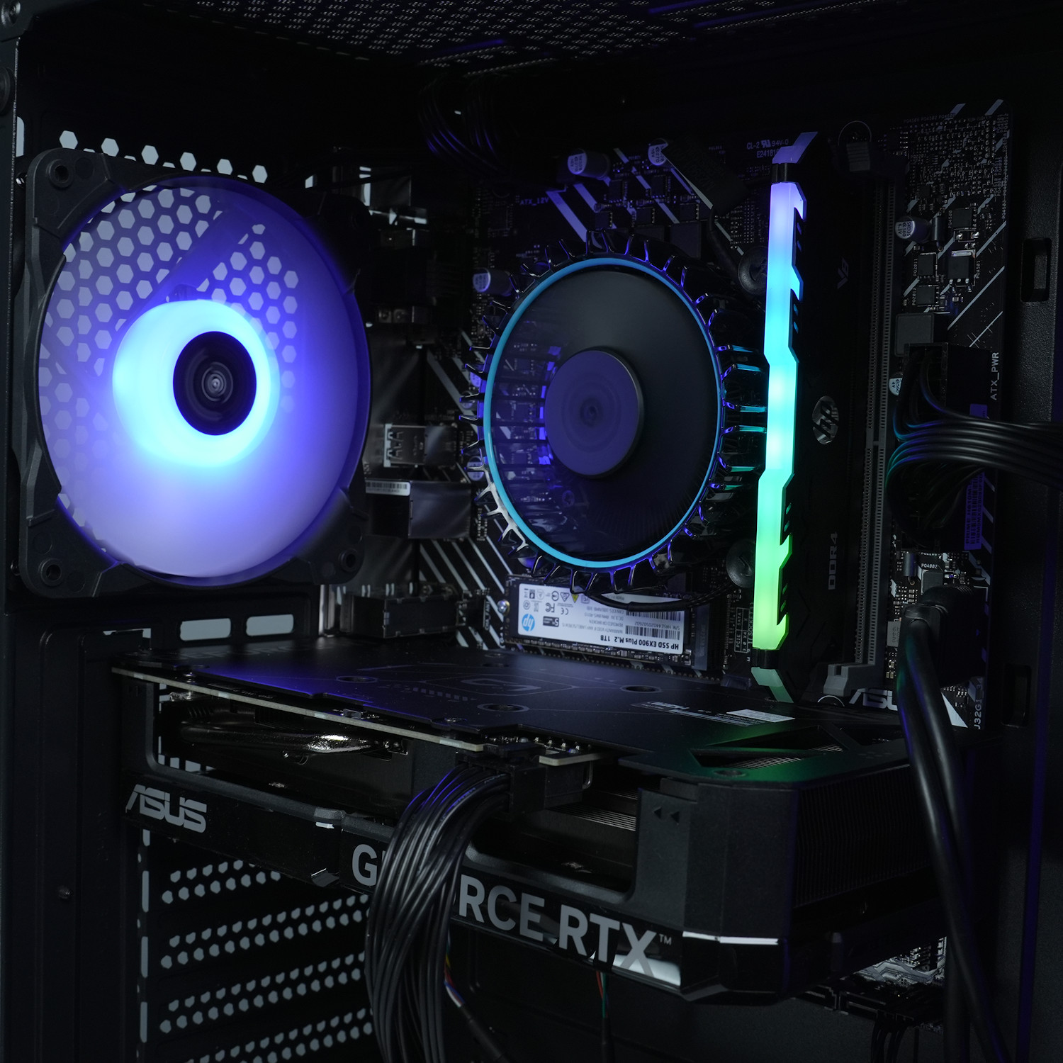 Componentes de PC dentro de una caja negra: ventiladores, una tarjeta gráfica y un enfriador de CPU. Luces azules y verdes.