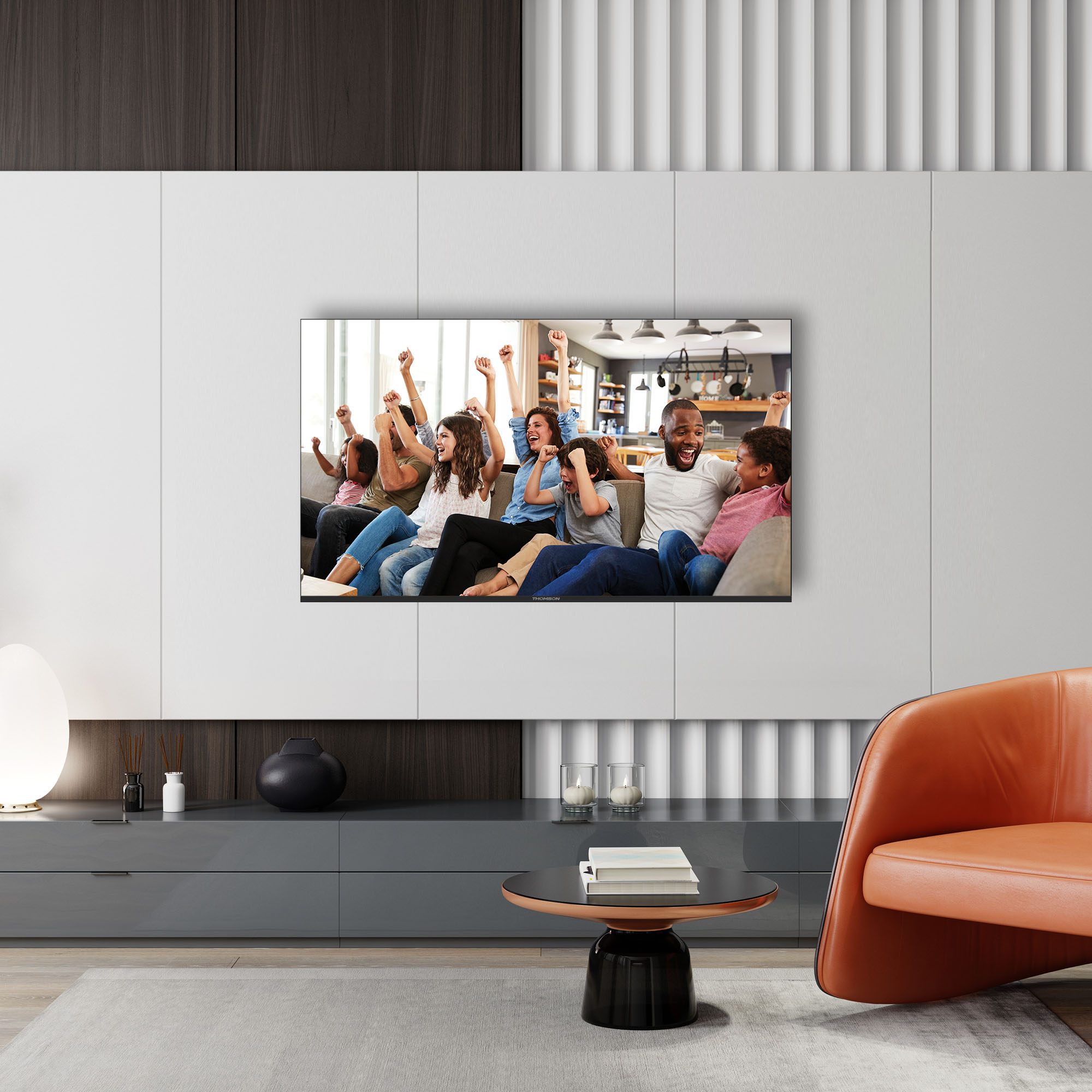 Rodzina ogląda telewizję, dopingując. Siedzą na kanapie. Telewizor jest zamontowany na białej ścianie.