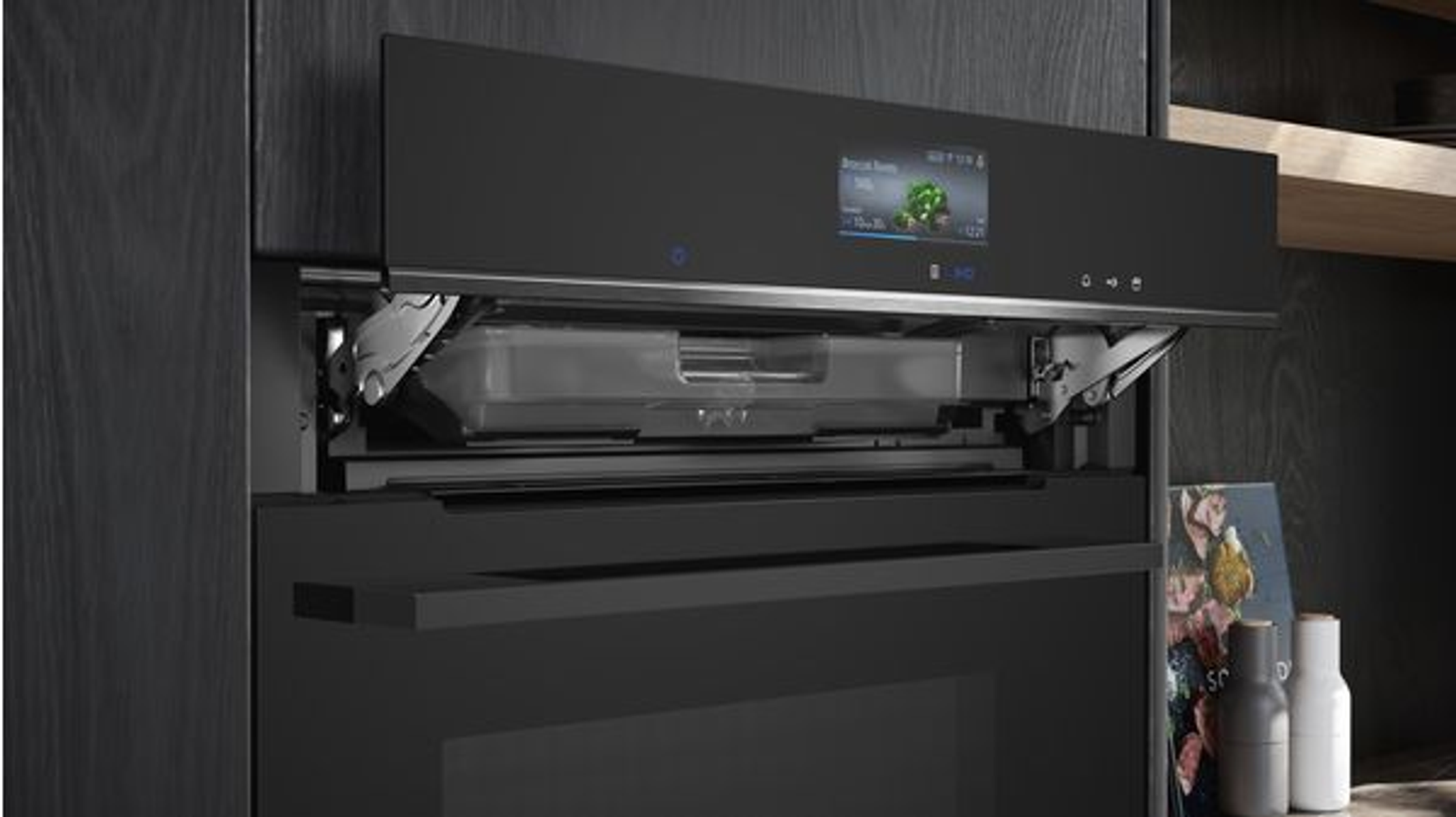 Four noir encastré avec un compartiment supérieur ouvert affichant un écran et un plateau.