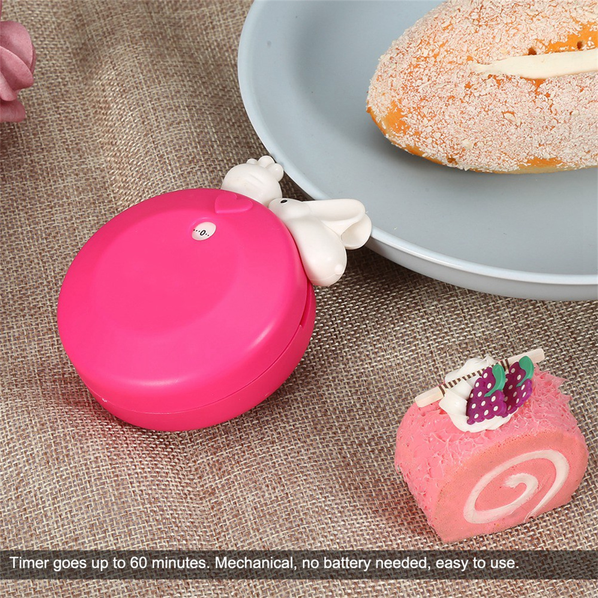 Ein pinkfarbener Küchentimer mit Hasenohren-Design und ein pinkfarbener Kuchen.