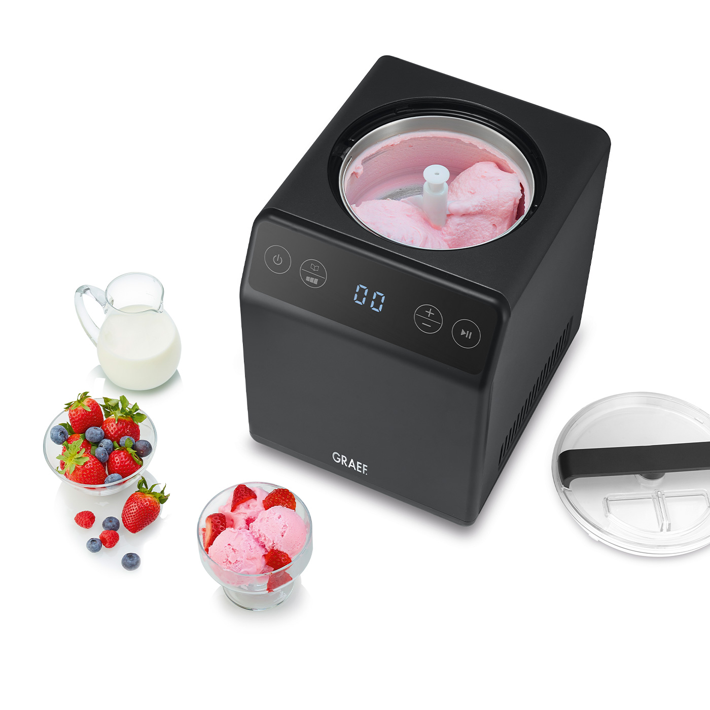Schwarze Eismaschine mit Zutaten wie Milch, Beeren auf weißer Oberfläche.