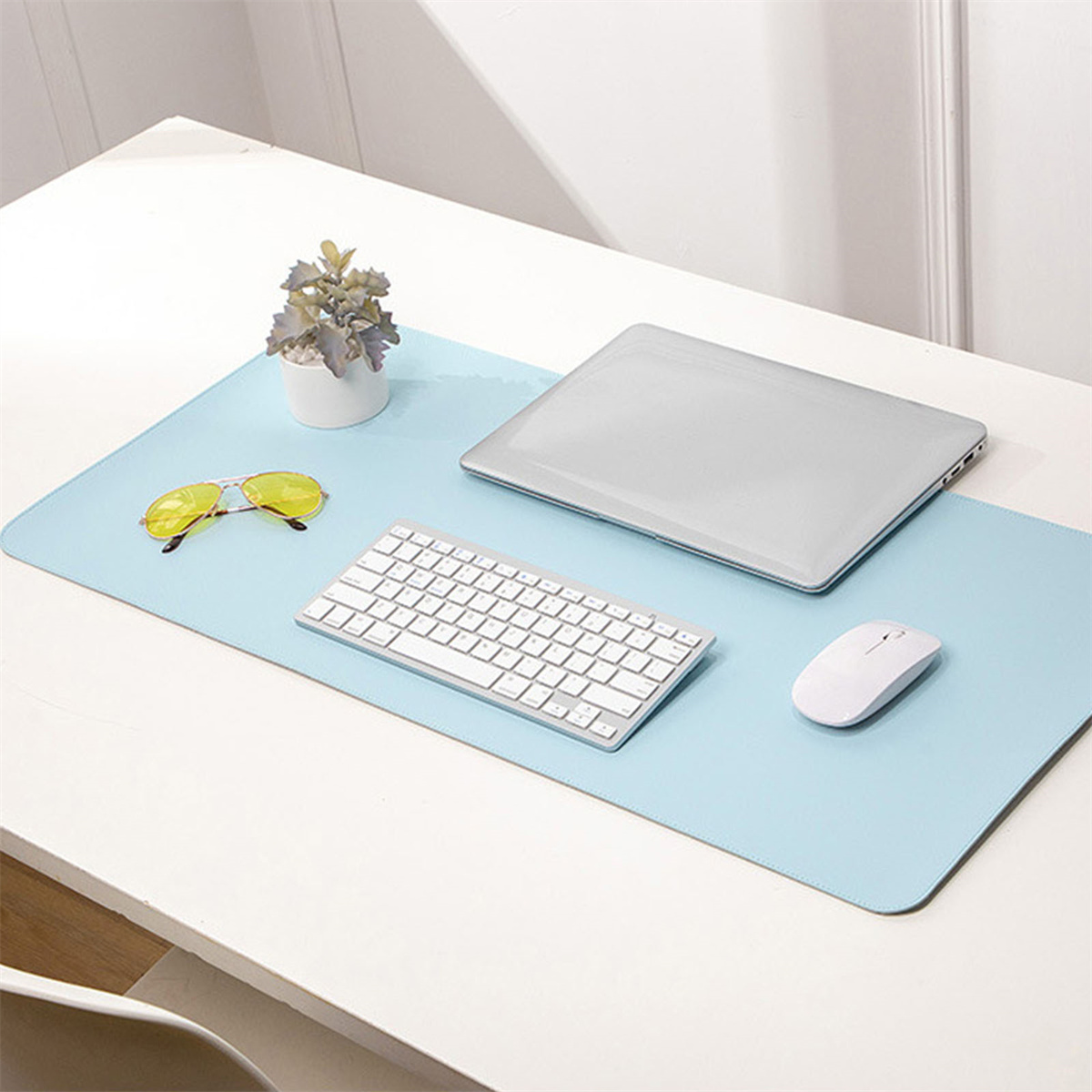 Ein Arbeitsplatz mit blauer Matte, Tastatur, Maus und Laptop. Es gibt gelbe Sonnenbrillen.