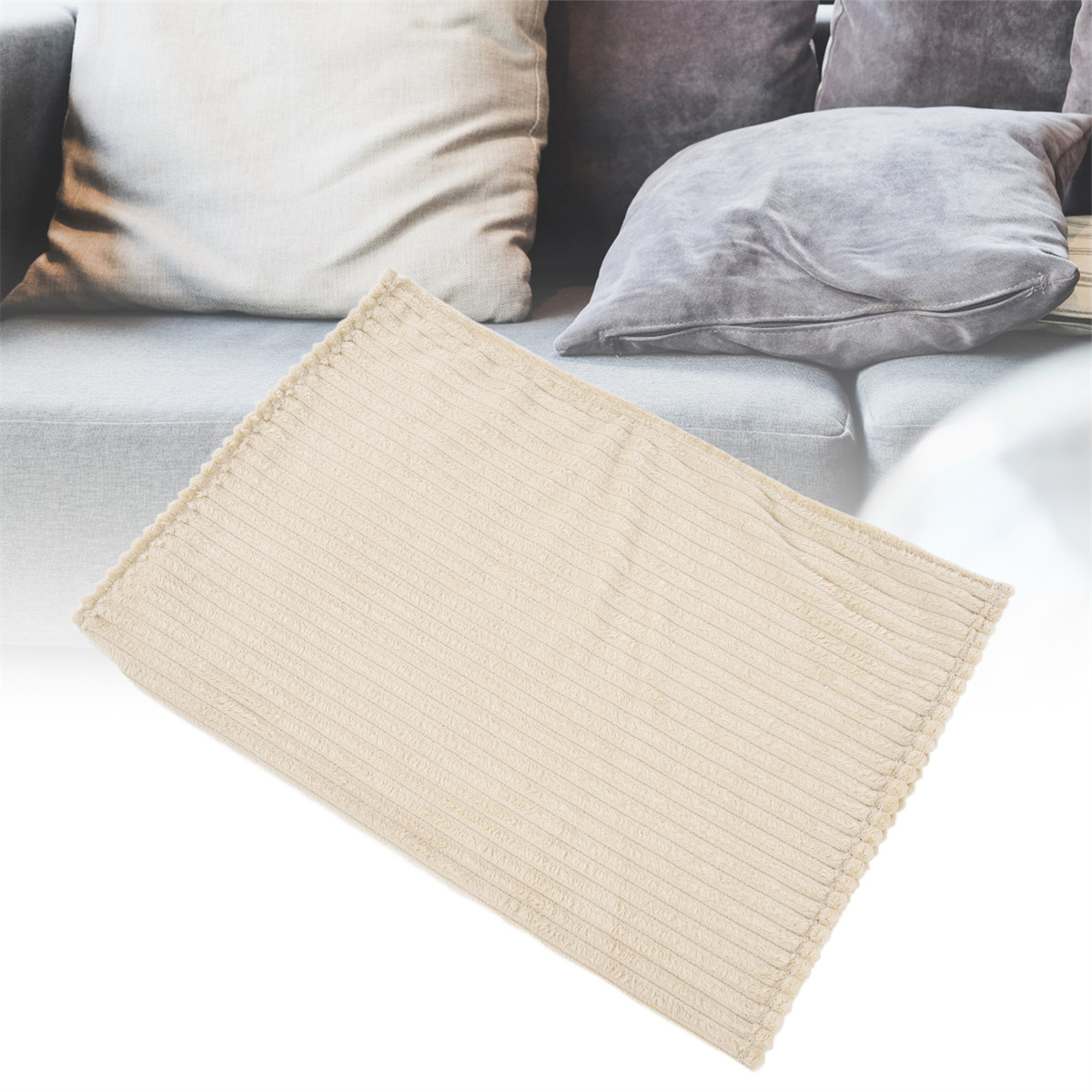 Beige Cord-Decke auf einem grauen Sofa.