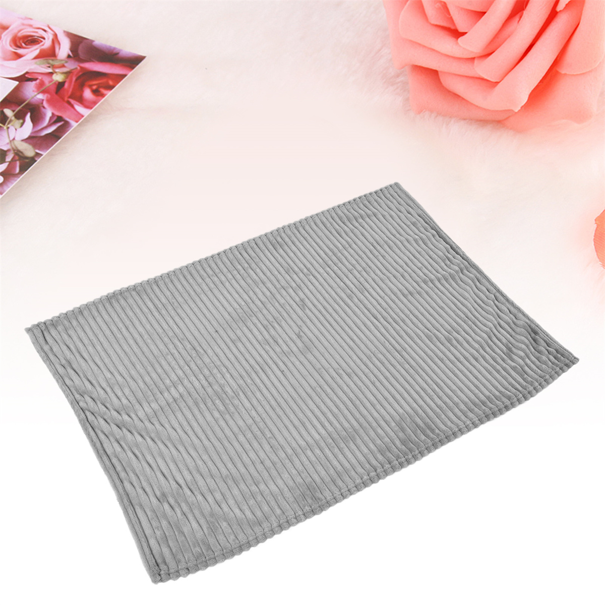 Grauer Cordteppich auf flauschiger Oberfläche mit Rosen im Hintergrund.