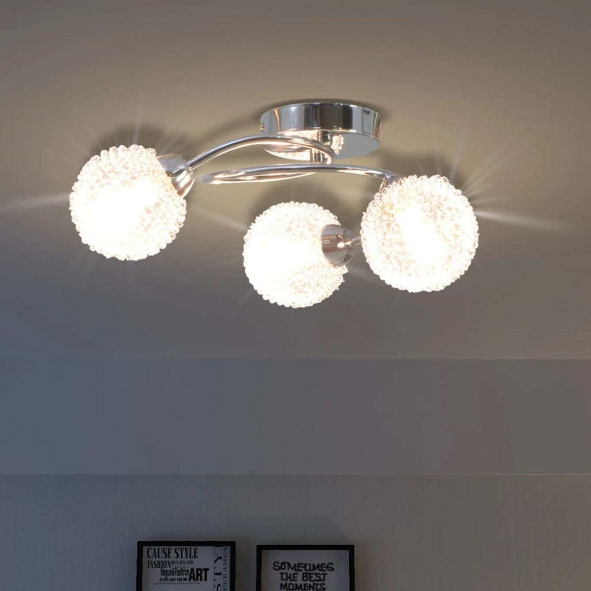 Lampada da soffitto con tre luci sferiche luminose, con finitura argentata, su uno sfondo neutro.