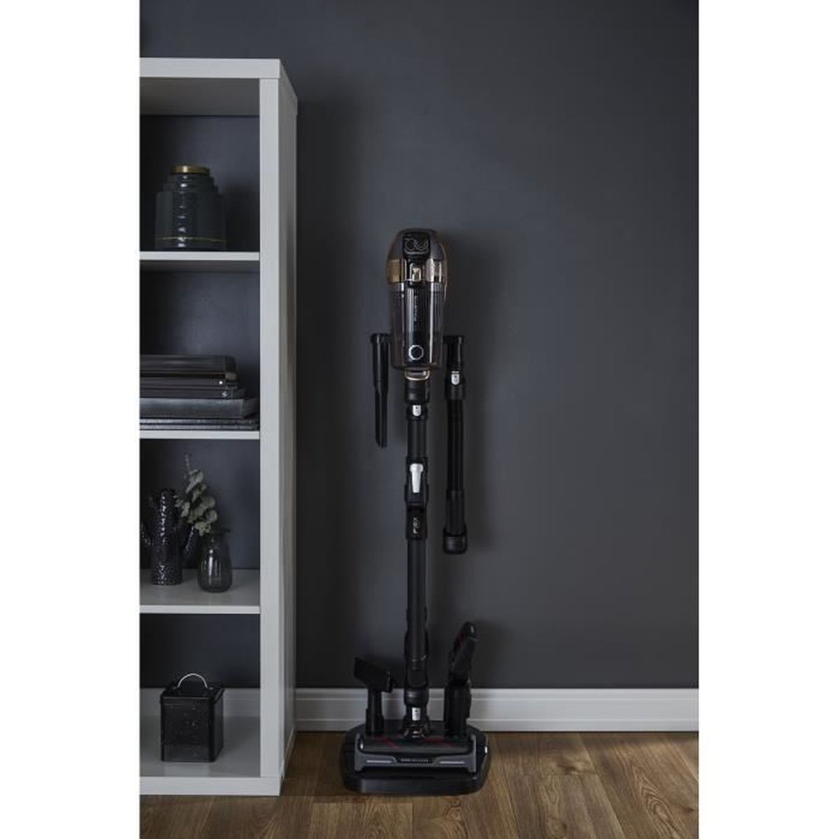 Czarny i złoty odkurzacz stojący pionowo, z akcesoriami i ciemną ścianą.