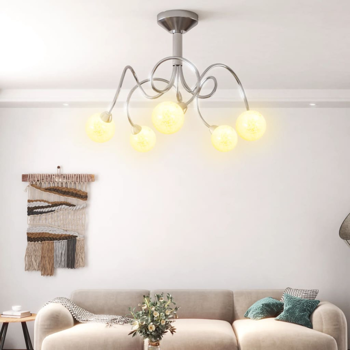 Un lampadario d'argento con sei luci a globo. Lo sfondo è un soffitto e una parete bianchi.