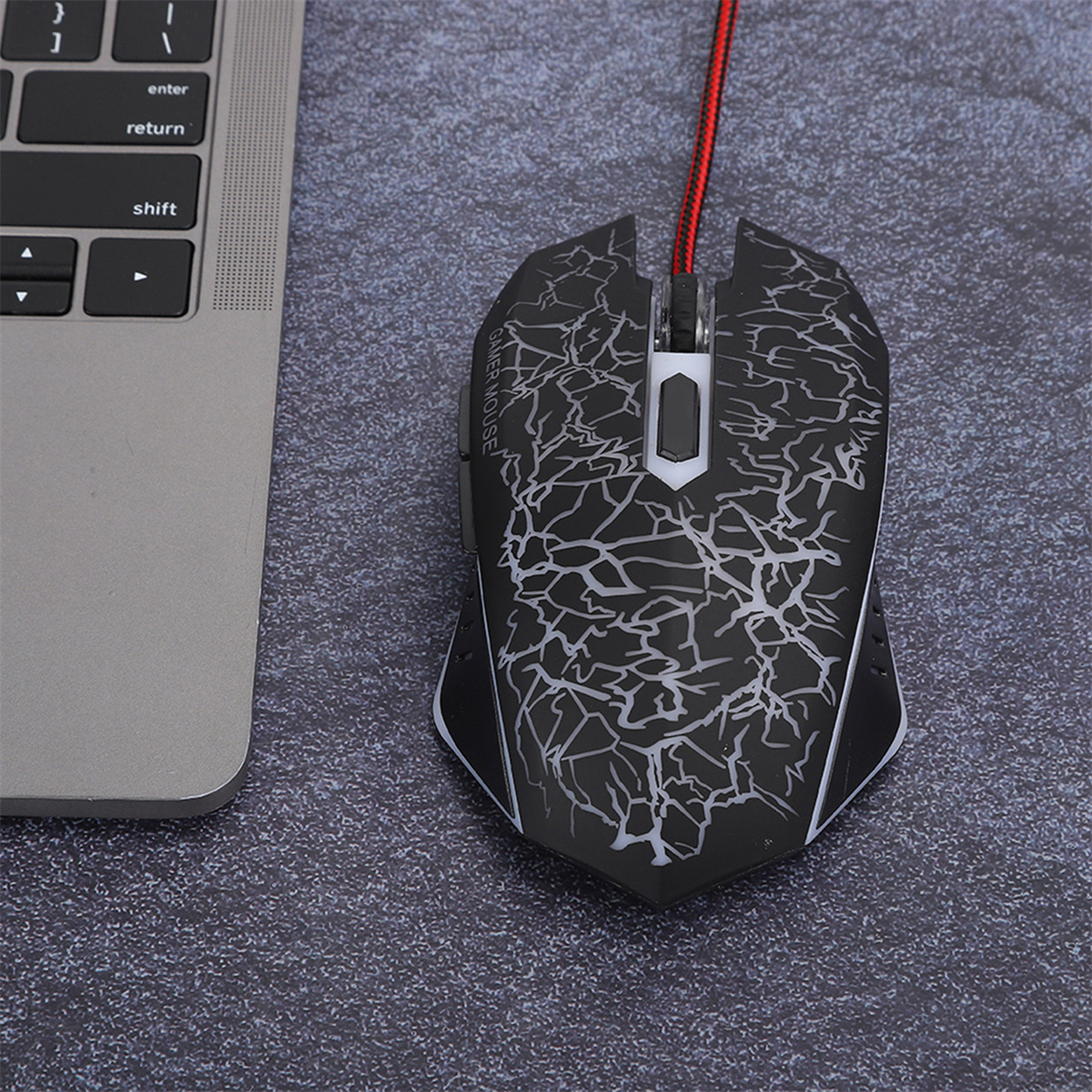 Schwarze Gaming-Maus mit weißem Blitzdesign, an einen Laptop angeschlossen.