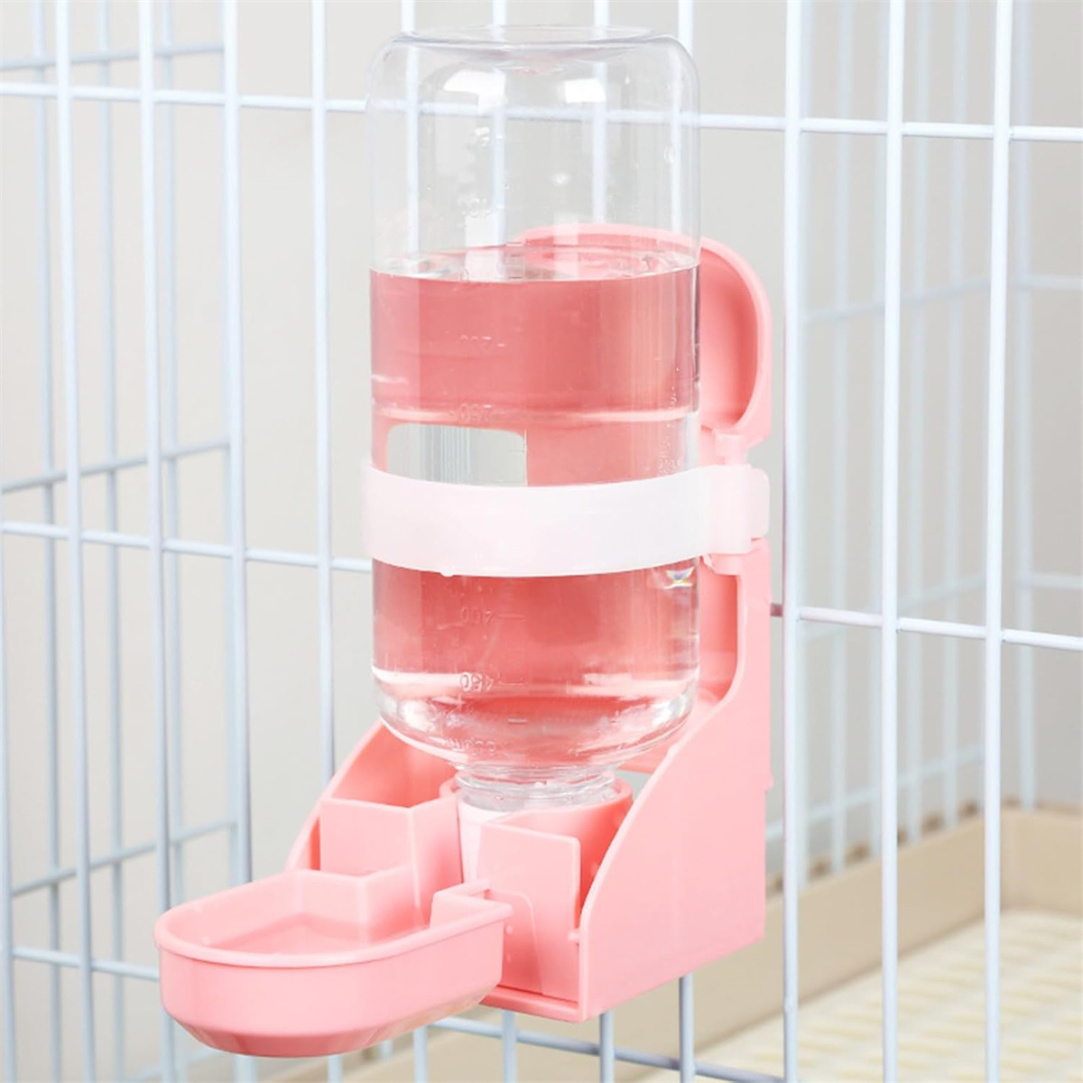 Rosa Wasserflasche mit kleiner Schale. Die Flasche ist in einem Käfig. Weißer Hintergrund.