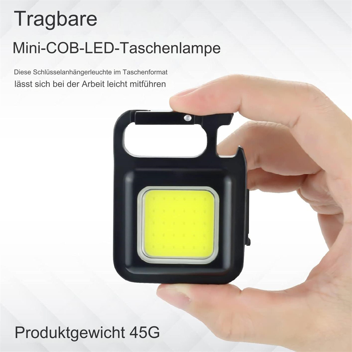Eine schwarze Mini-LED-Taschenlampe, gehalten von einer Hand. Sie hat ein gelbes Licht und einen Karabiner.