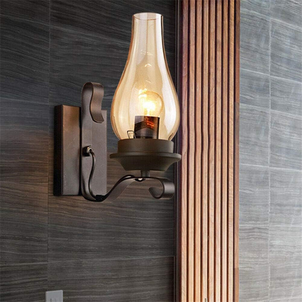 Wandlampe mit Glasschirm und brennender Glühbirne, an einer strukturierten grauen Wand montiert.