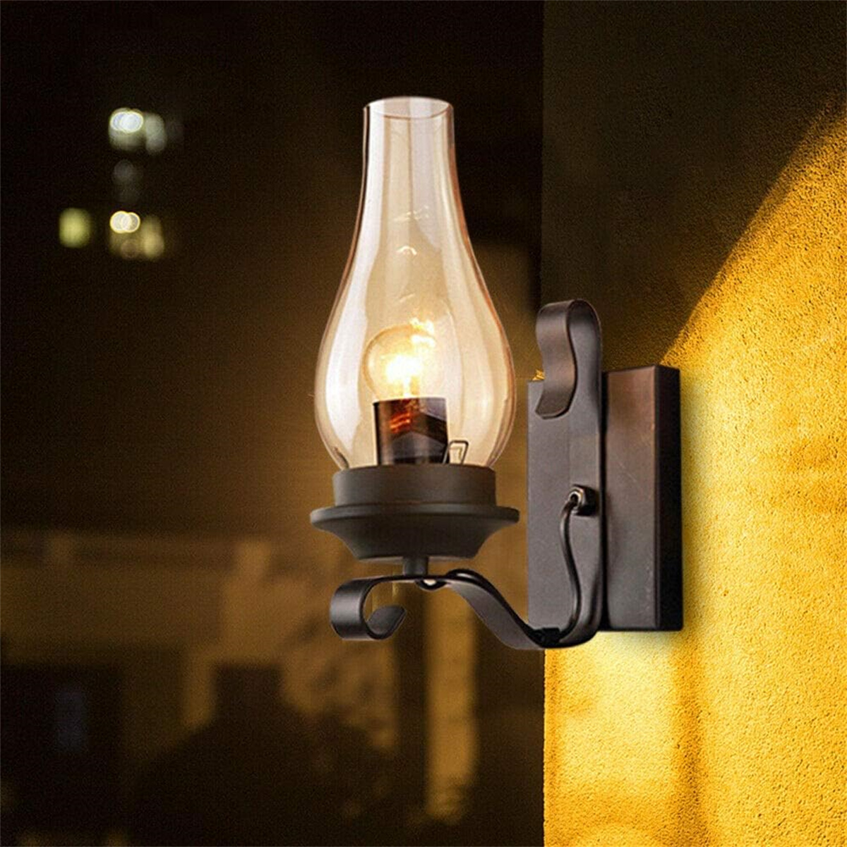 Eine Wandlampe im antiken Stil mit einem durchsichtigen Glasschirm und einem schwarzen Metallrahmen.