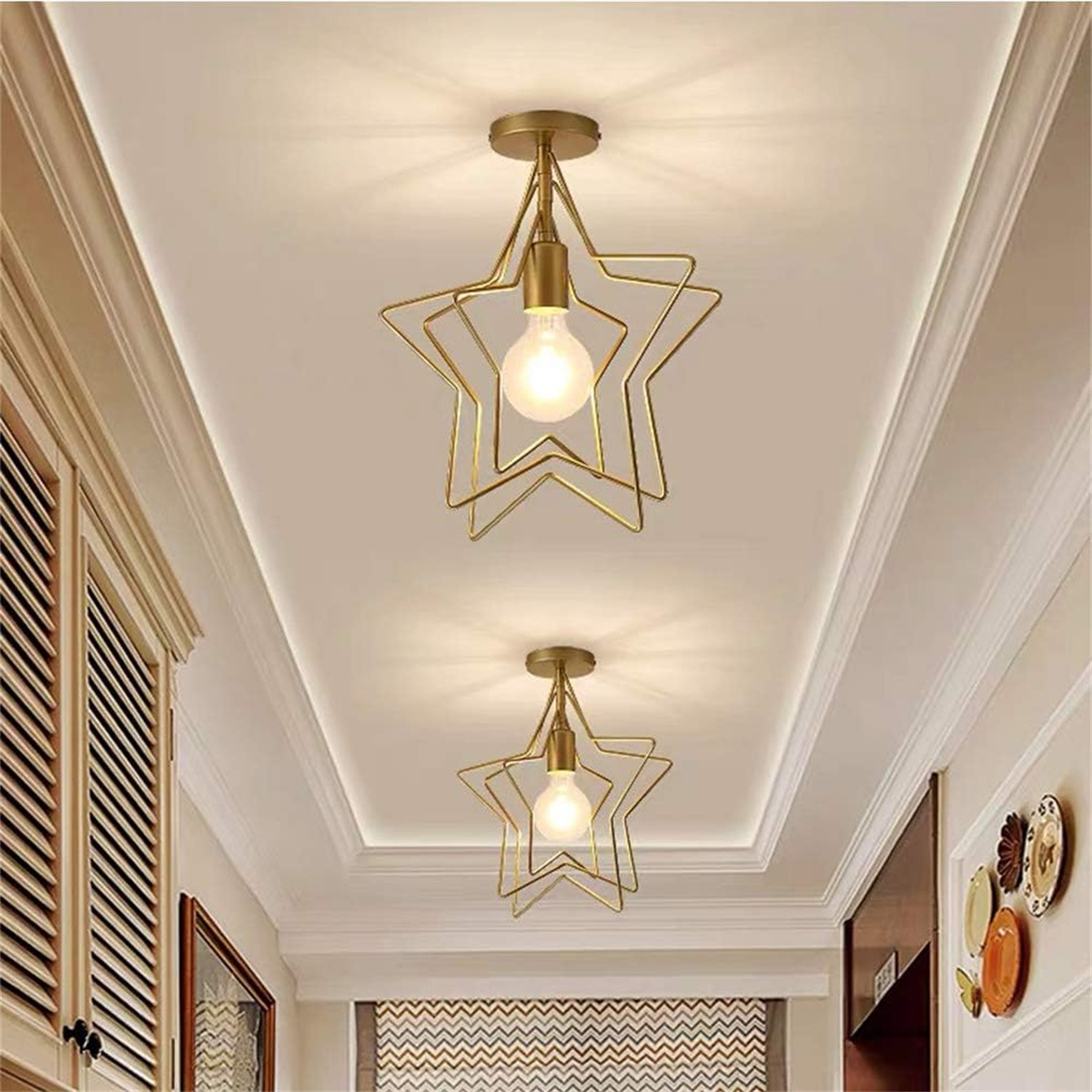 Zwei sternförmige goldene Pendelleuchten hängen von einer weißen Decke. Die Szene ist gut beleuchtet.