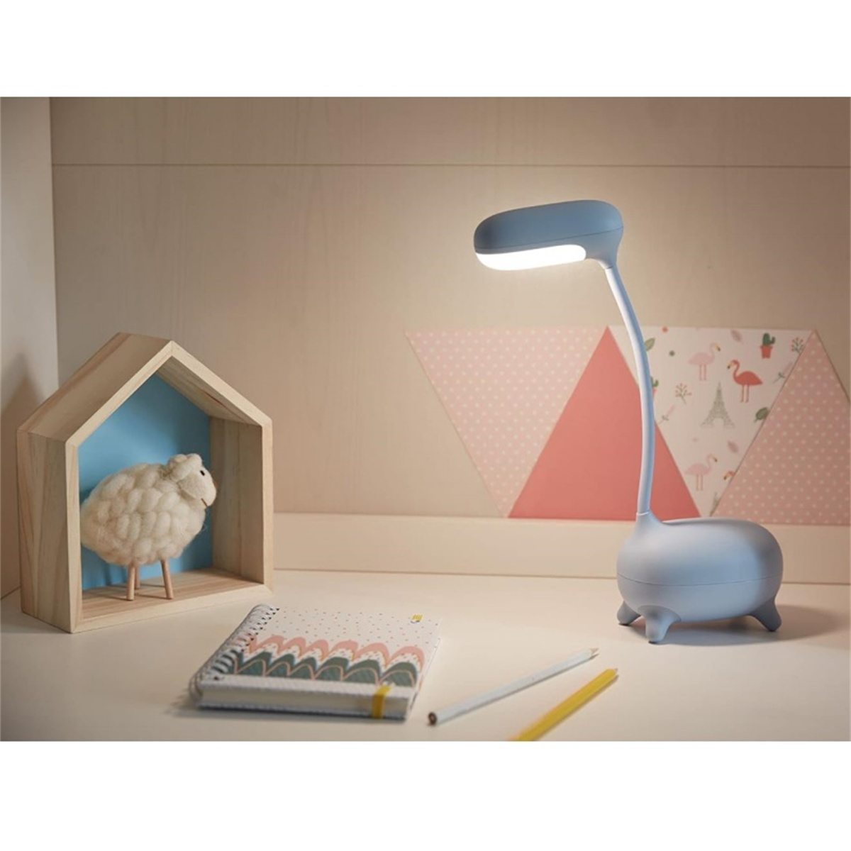 Blaue Schreibtischlampe mit Schwanenhals, Holzhaus und Schaf-Figur auf einem Schreibtisch.