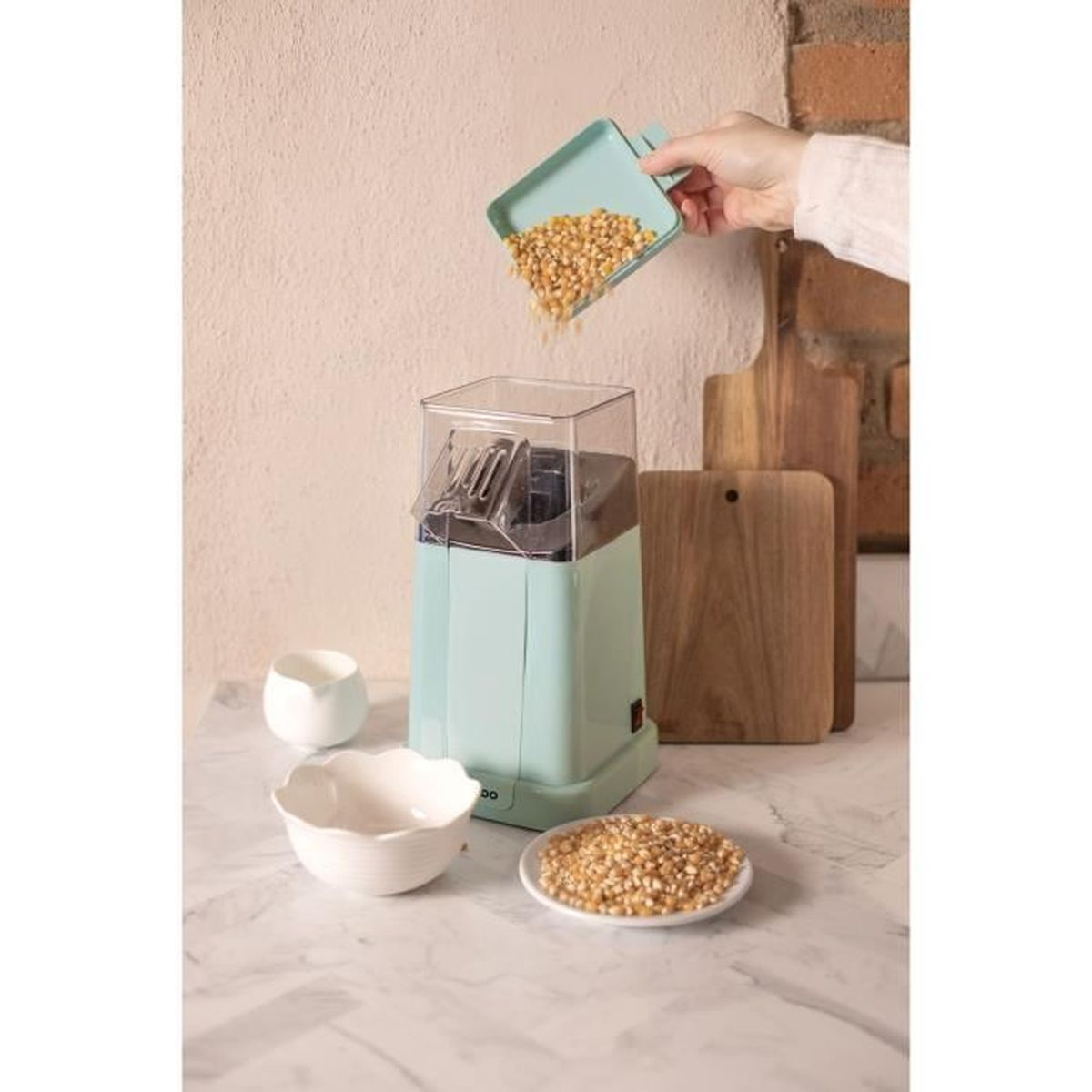 Popcornmaschine mit Popcorn und Maiskörnern, jemand schüttet Körner ein.