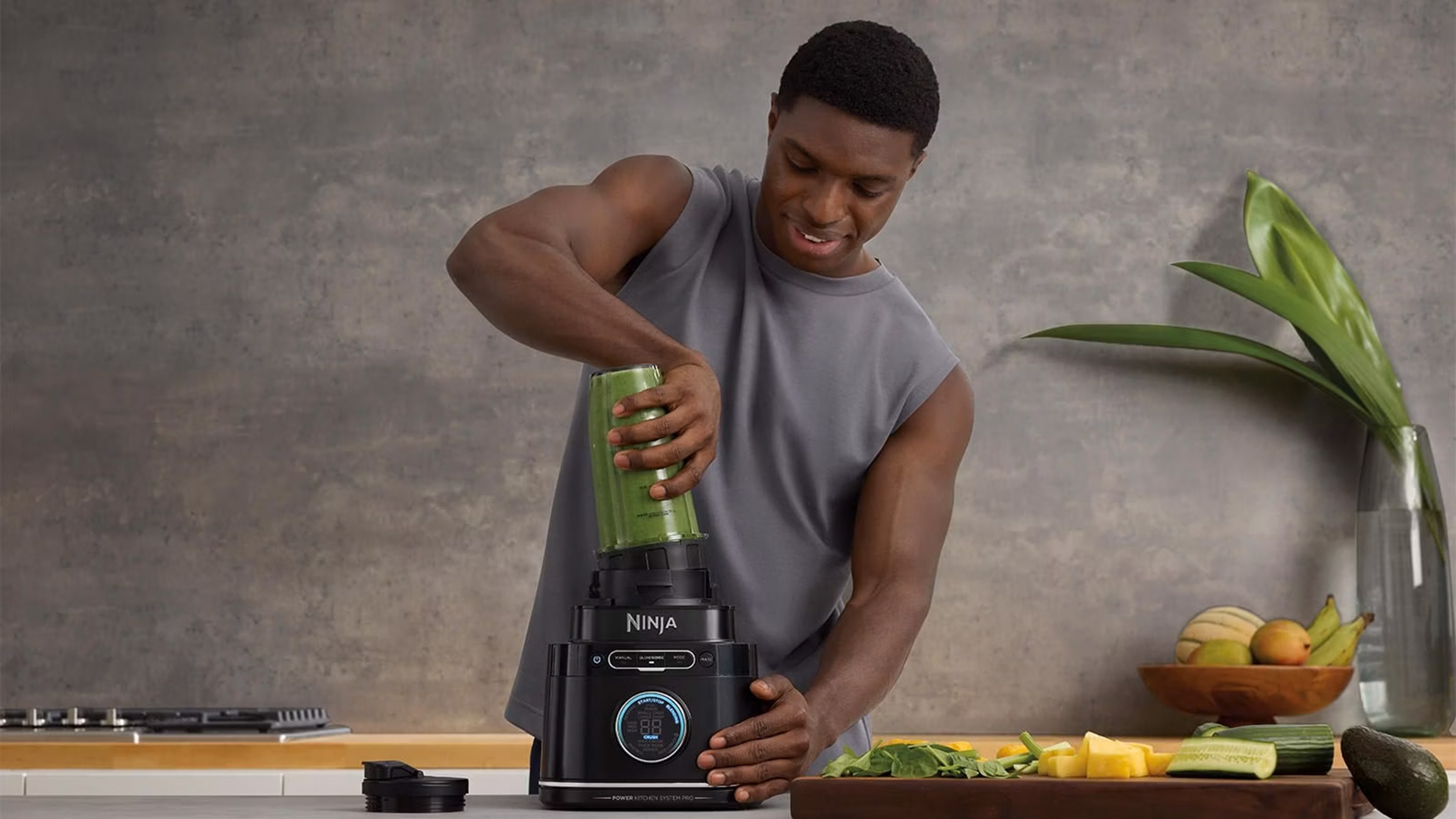 Mężczyzna przygotowuje koktajl za pomocą blendera na blacie. Składniki są na blacie.