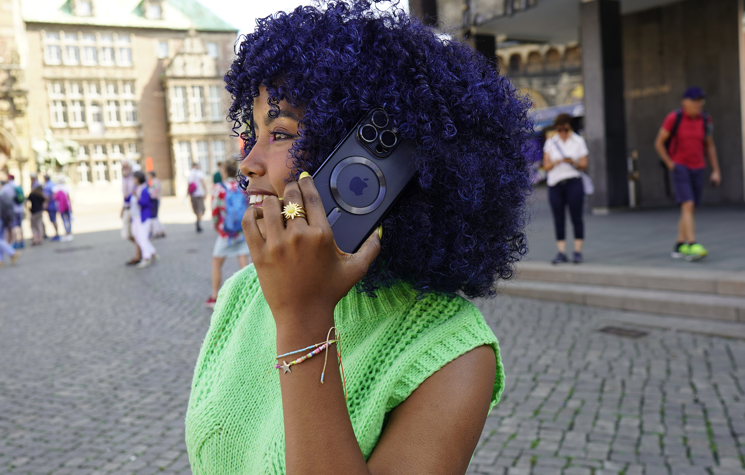 Eine Frau mit lilafarbenem Haar telefoniert und hält ein Telefon mit Magnetbefestigung in einer Stadt.