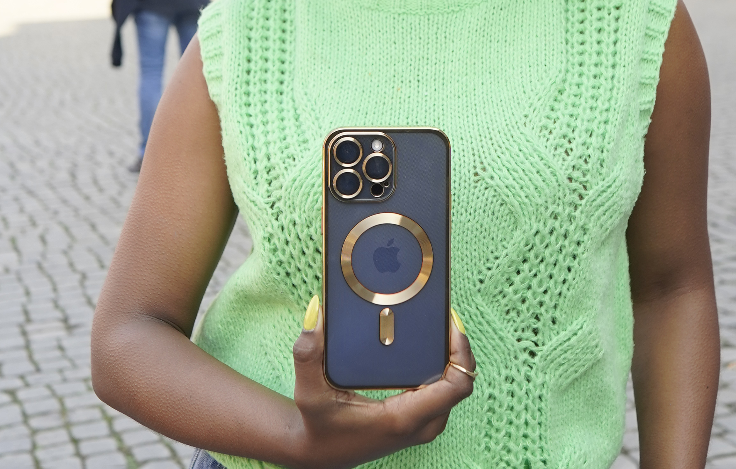 Eine Person hält ein schwarzes iPhone mit goldener Hülle und goldenem Apple-Logo.