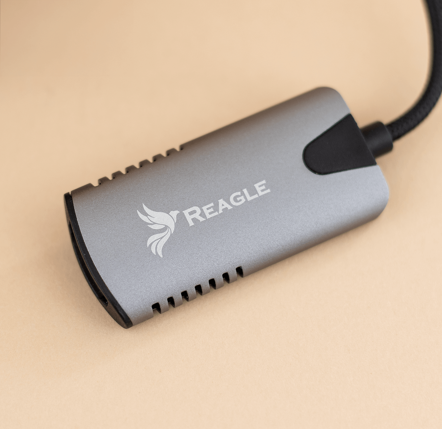 Srebrnoszare urządzenie REAGLE z logo i czarnym kablem.