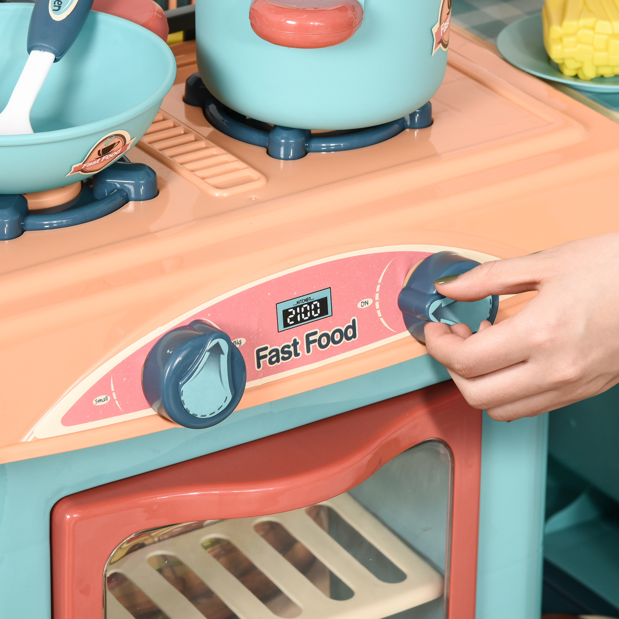 Una cocina de juguete para niños con un panel de control y una mano girando una perilla.