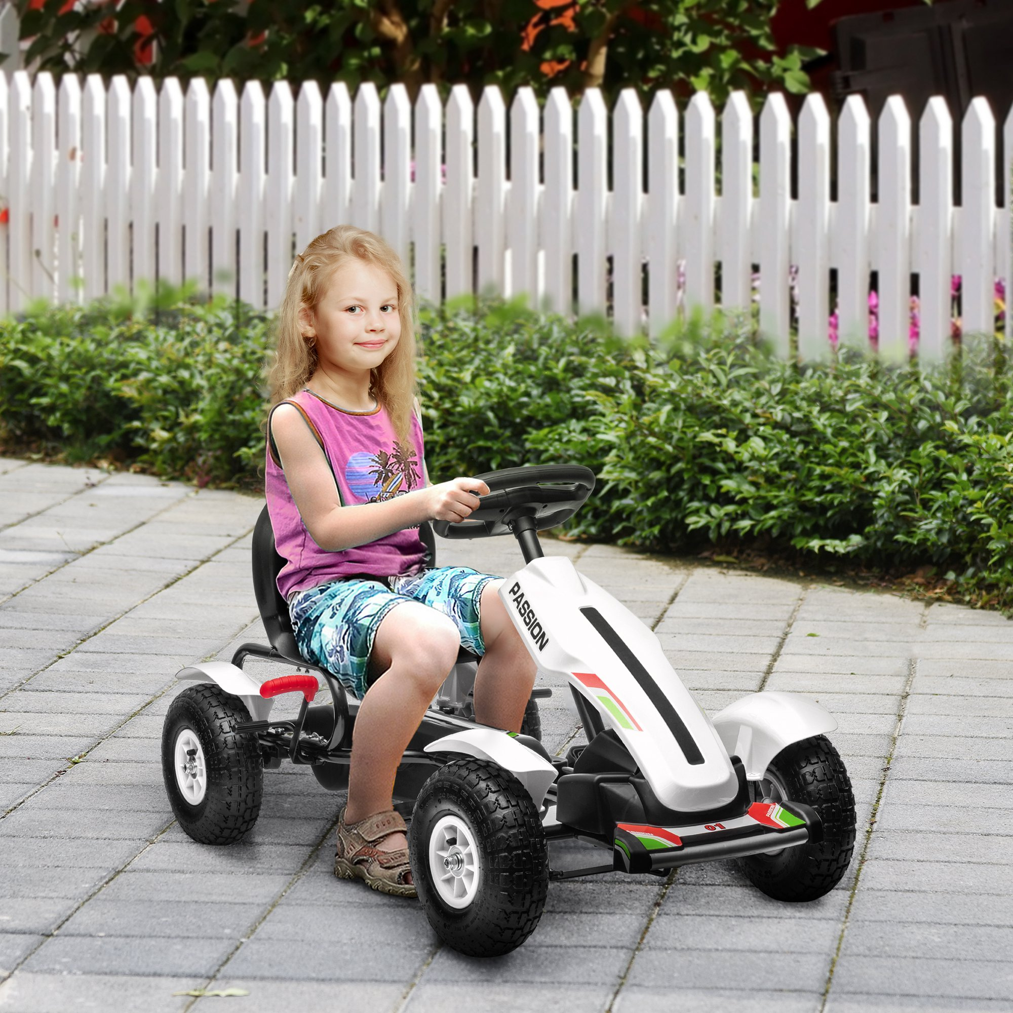 Una niña conduciendo un kart blanco en un camino pavimentado.