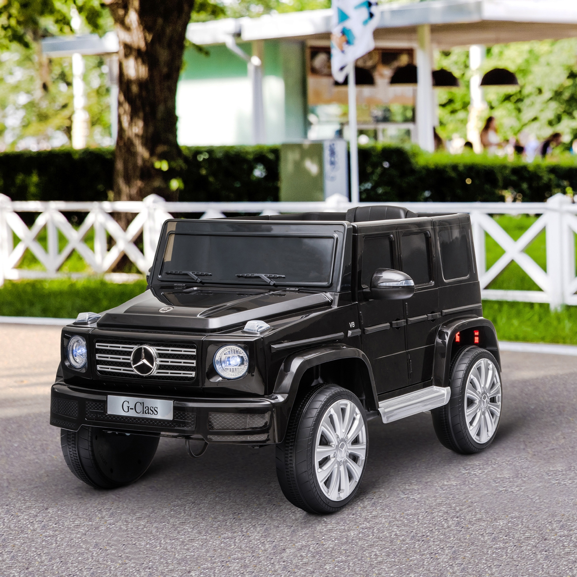 Coche de juguete negro en forma de G-Class con valla blanca al fondo.