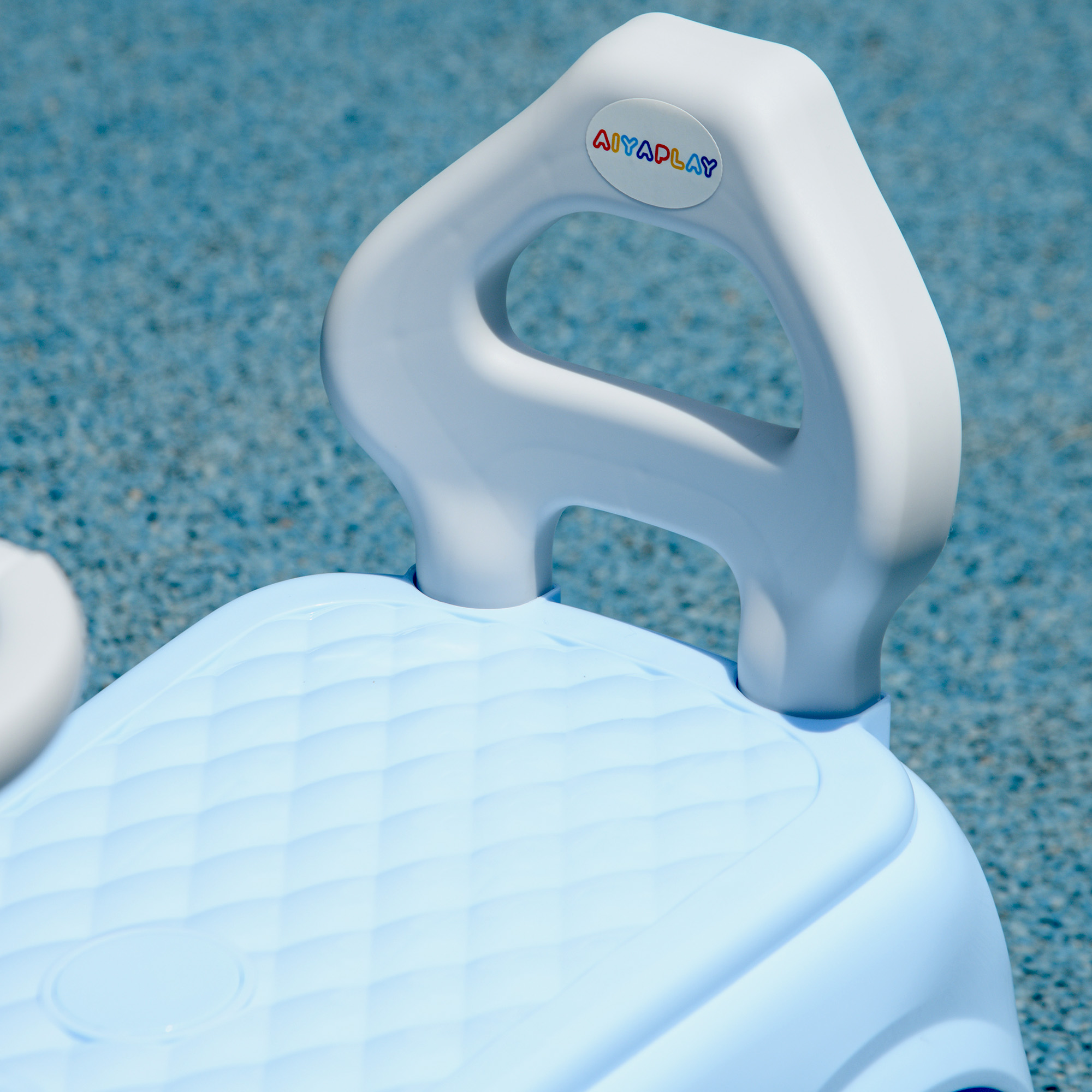Primer plano de un asiento de bebé azul claro con un asa blanca. El fondo es una superficie azul.