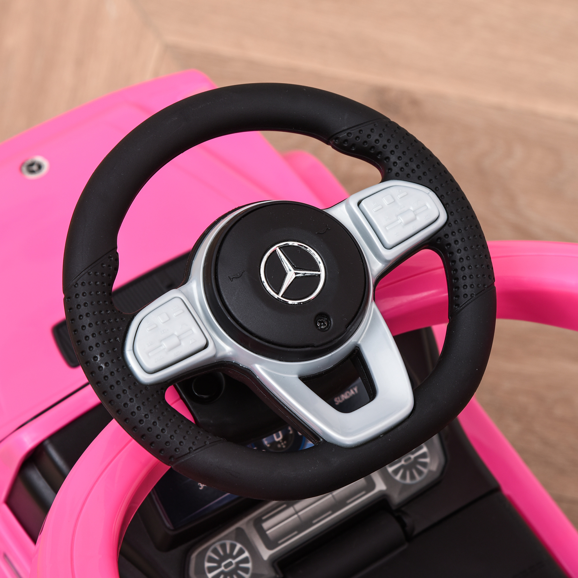 Un volante de un coche de juguete rosa, con detalles plateados.