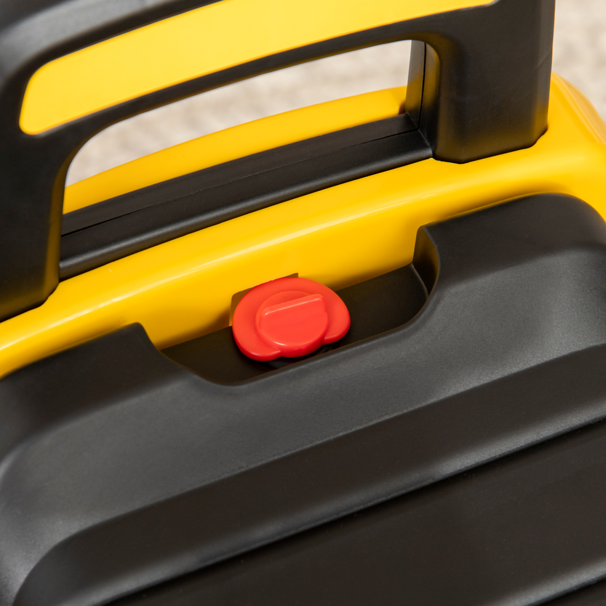 Primo piano: Maniglia in plastica gialla e nera con un pulsante rosso.